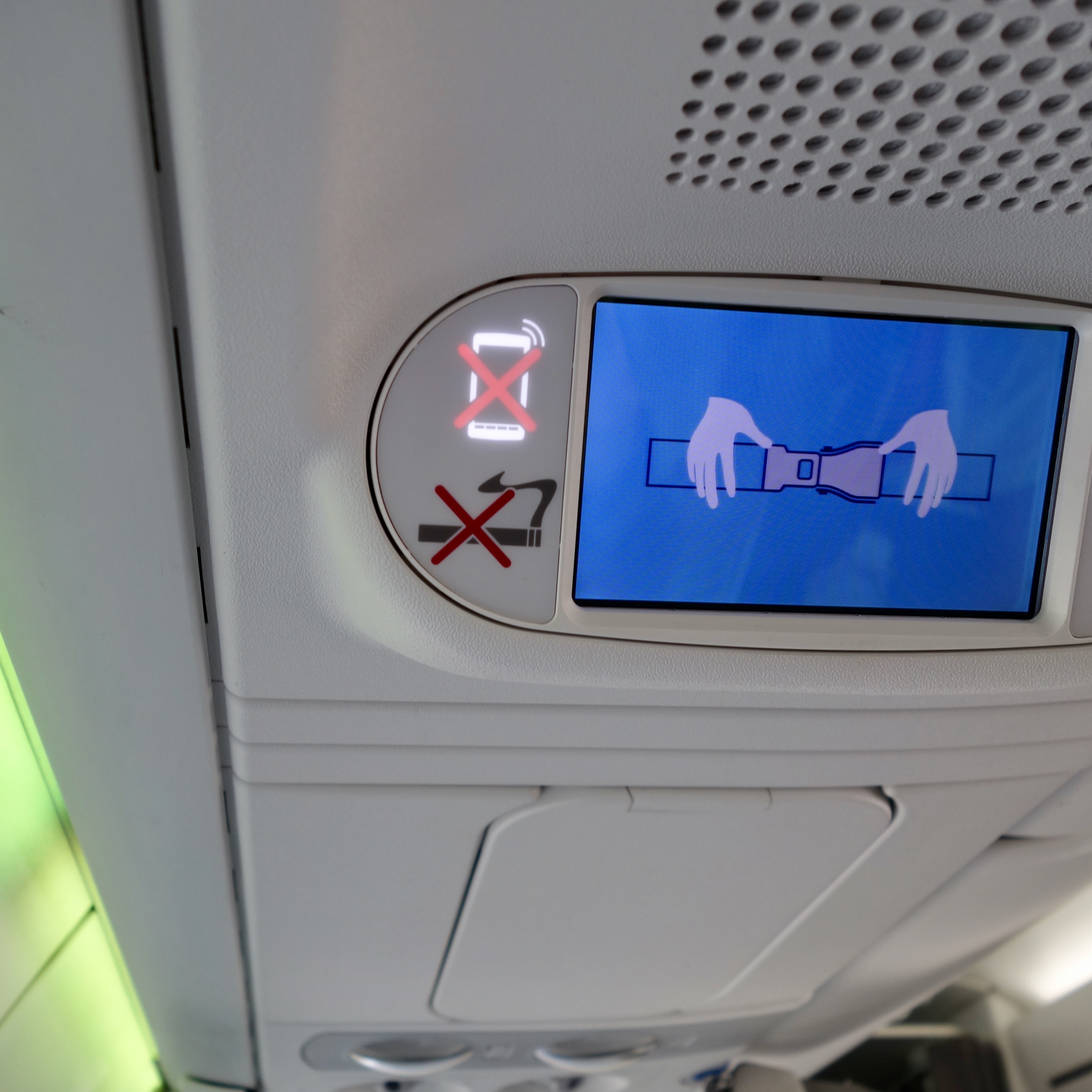 The Airbus A220 is a modern aircraft and this review reveals ipad sized screen behind each seat displaying in flight information, including safety features like this cartoon depicting buckling seatbelts, no smoking and no cell phones. 