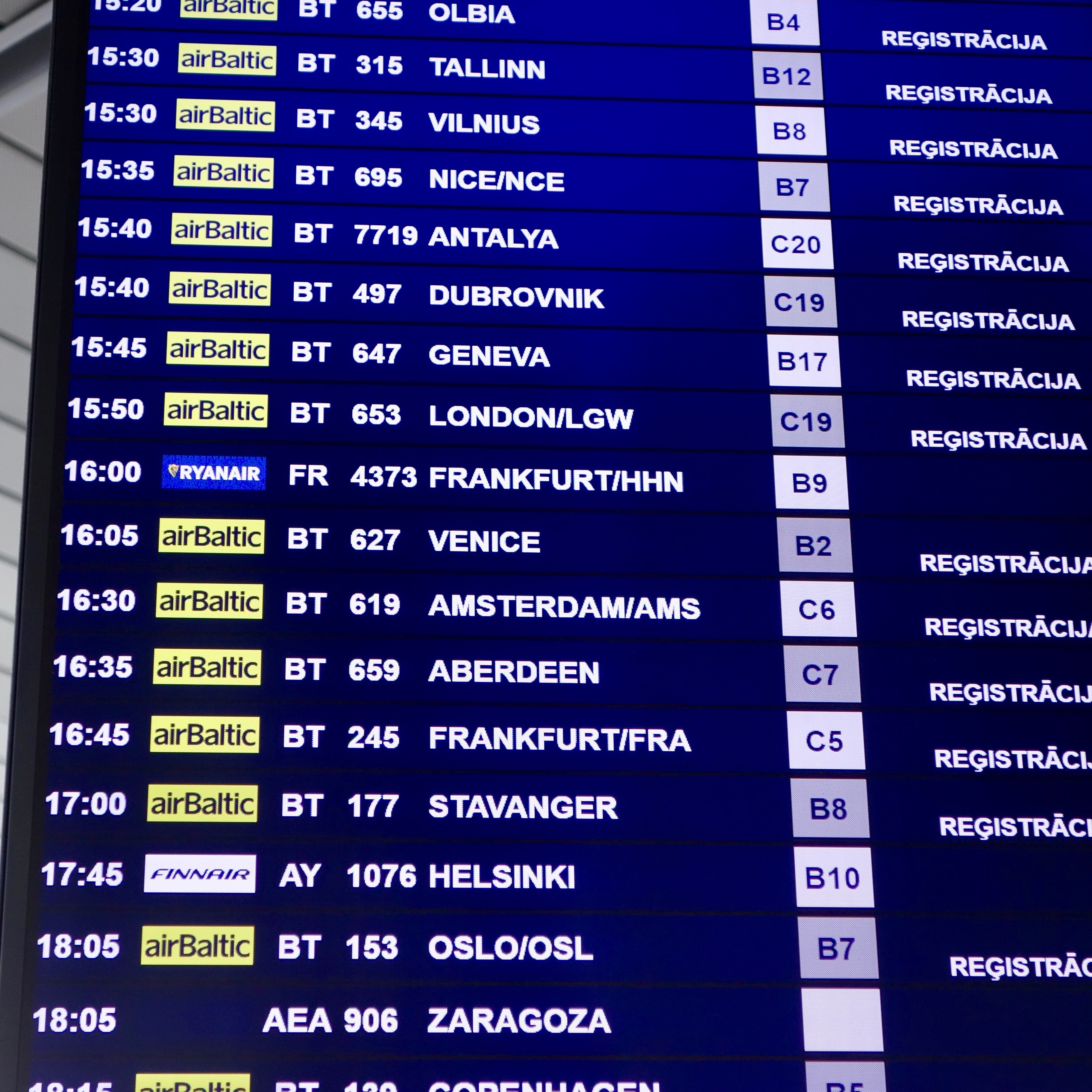 An airport video display of flights highlights the hub at Riga Airport in Latvia.  A wide majority of the flights are operated by airBaltic, which shows up in the signature chartreuse green against a dark blue background with white lettering.  
