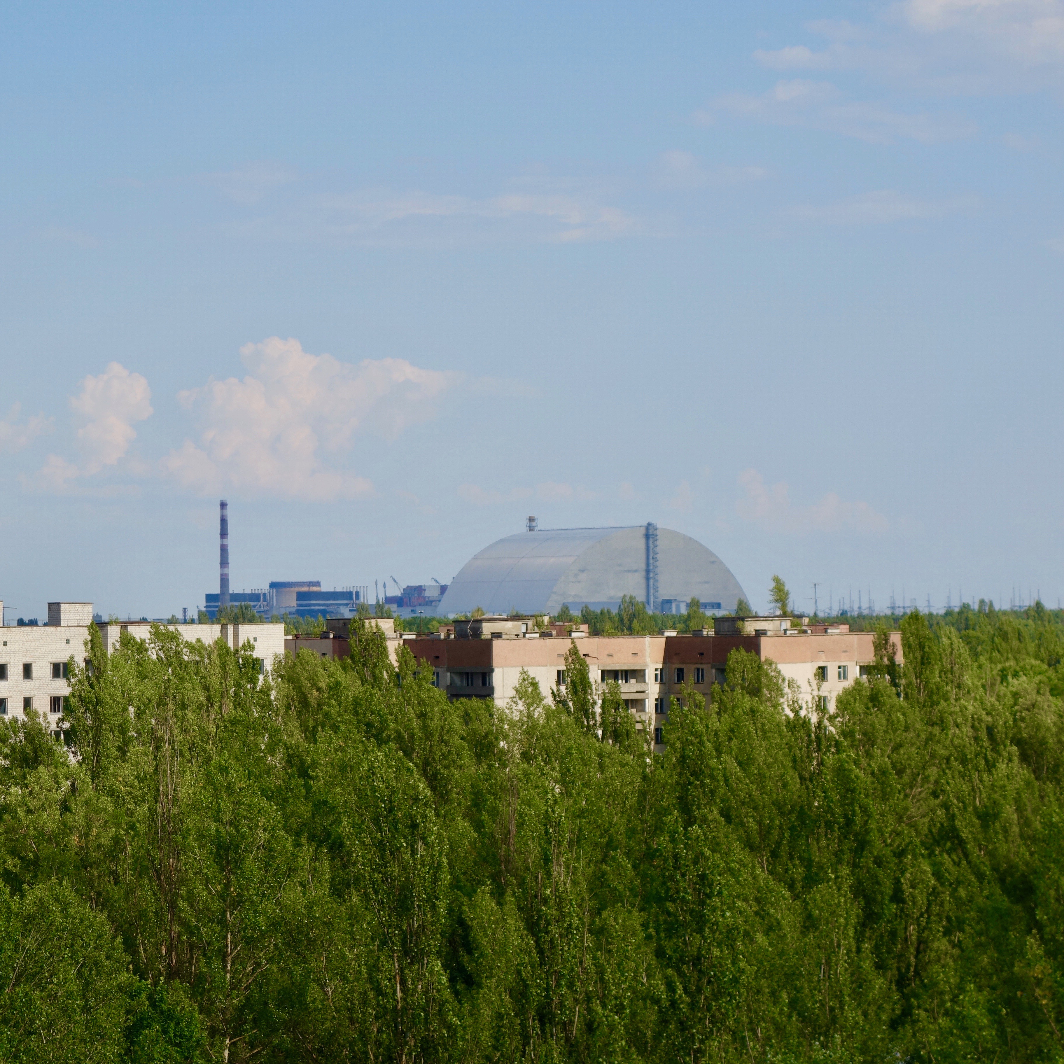 View from the rooftop of one of the many empty apartment buildings in the ghost town of Prypriat.  In the background you can see the stainless steel sarcophagus covering the melted down Chernobyl Reactor number four, exploded in April 1986.  