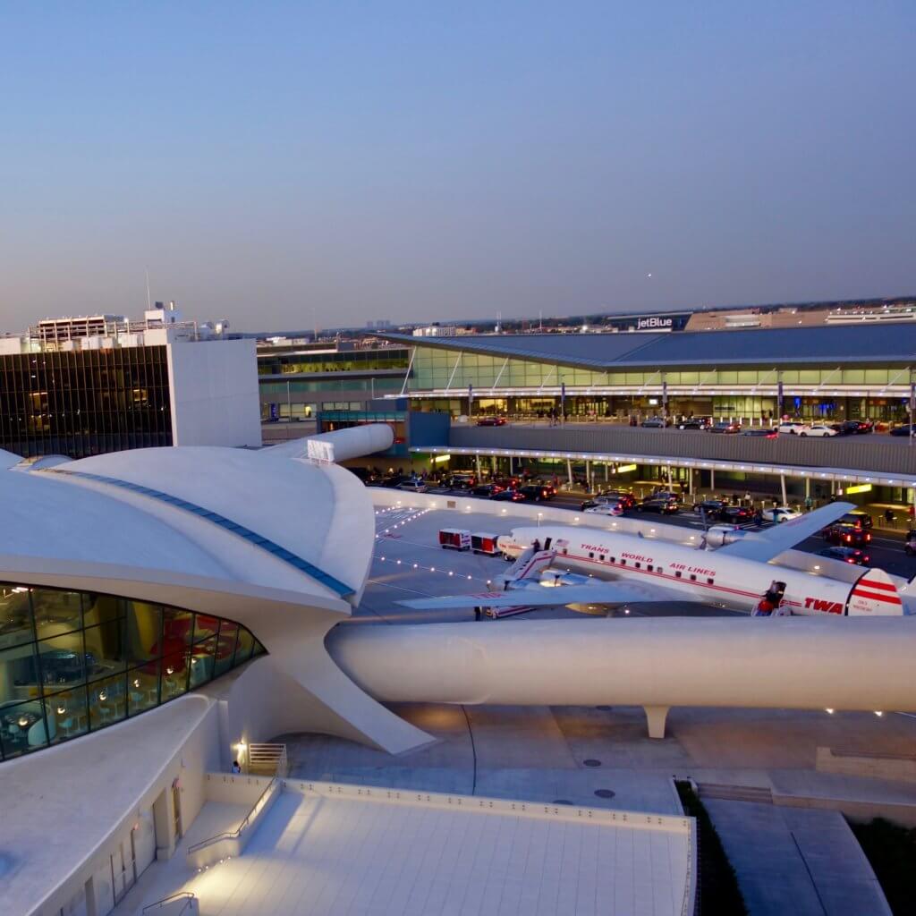 View looking down from the pool deck of the TWA Hotel over looking the iconic Eero Saarinen JFK Airport Terminal completed in 1962 for TWA. Outside the terminal is a vintage TWA Super Constellation, also know as the "Connie."