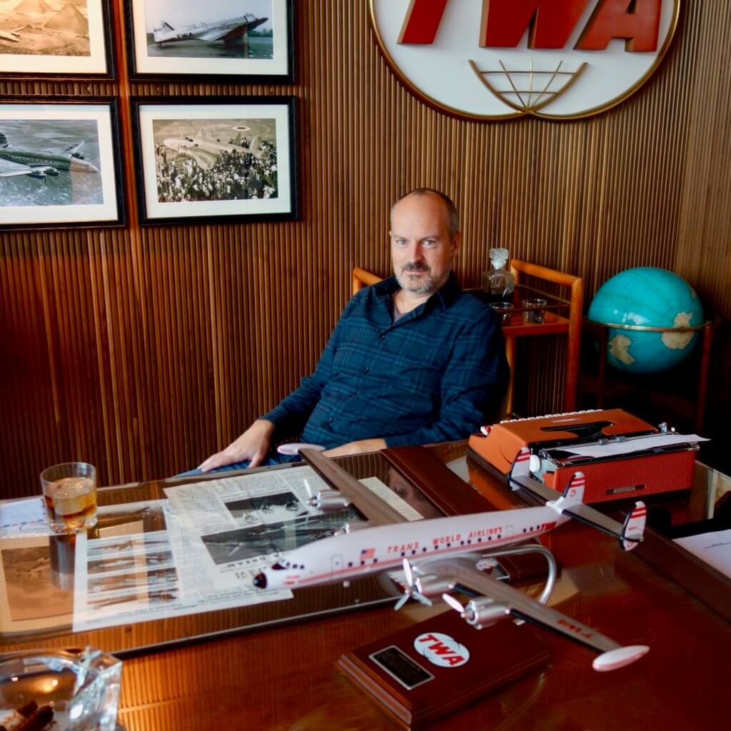 As you enter the TWA Hotel from Terminal 5 there is a replica of Howard Hughes' TWA office. Here I sit at his desk with a model airplane and much more TWA nostalgia.