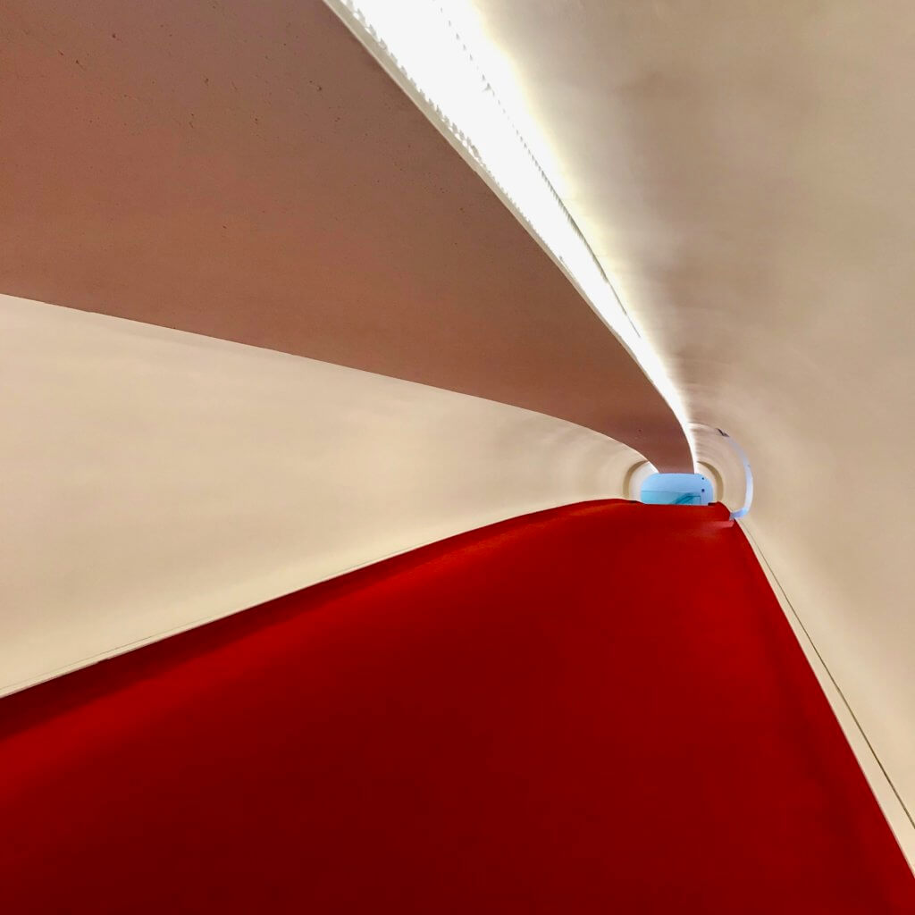 This corridor with the iconic TWA red carpet connects the modern day Terminal 5 with the historic Eero Saarinen terminal building completed in 1962 for TWA.
