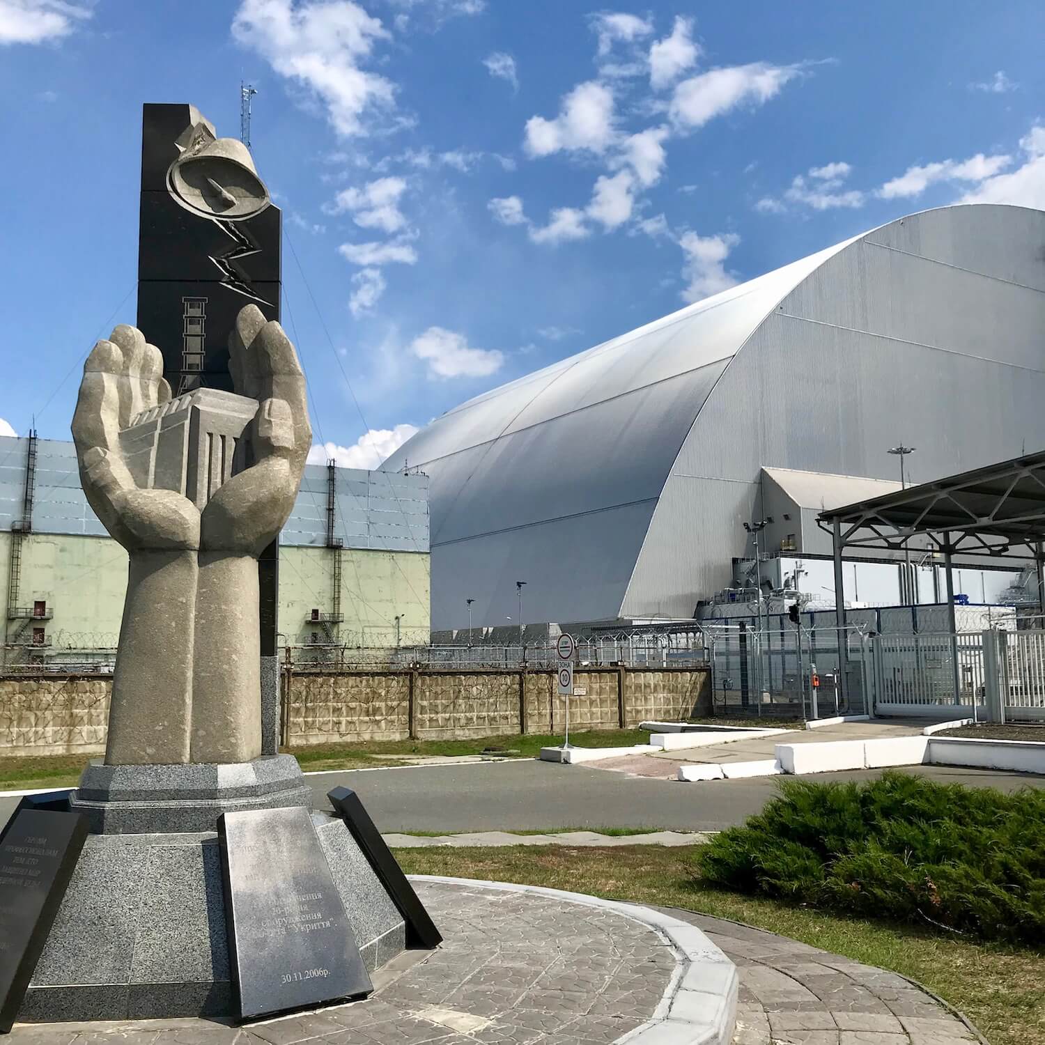 A monument to commemorate the tragic steam explosion at Chernobyl Reactor #4 that took place in April 1986. The monument is a sculpted hand reaching out from a granite pedestal. In the hand is a building that represents the reactor. The the background behind the monument is the new titanium sarcophagus which covers the remains of the reactor.