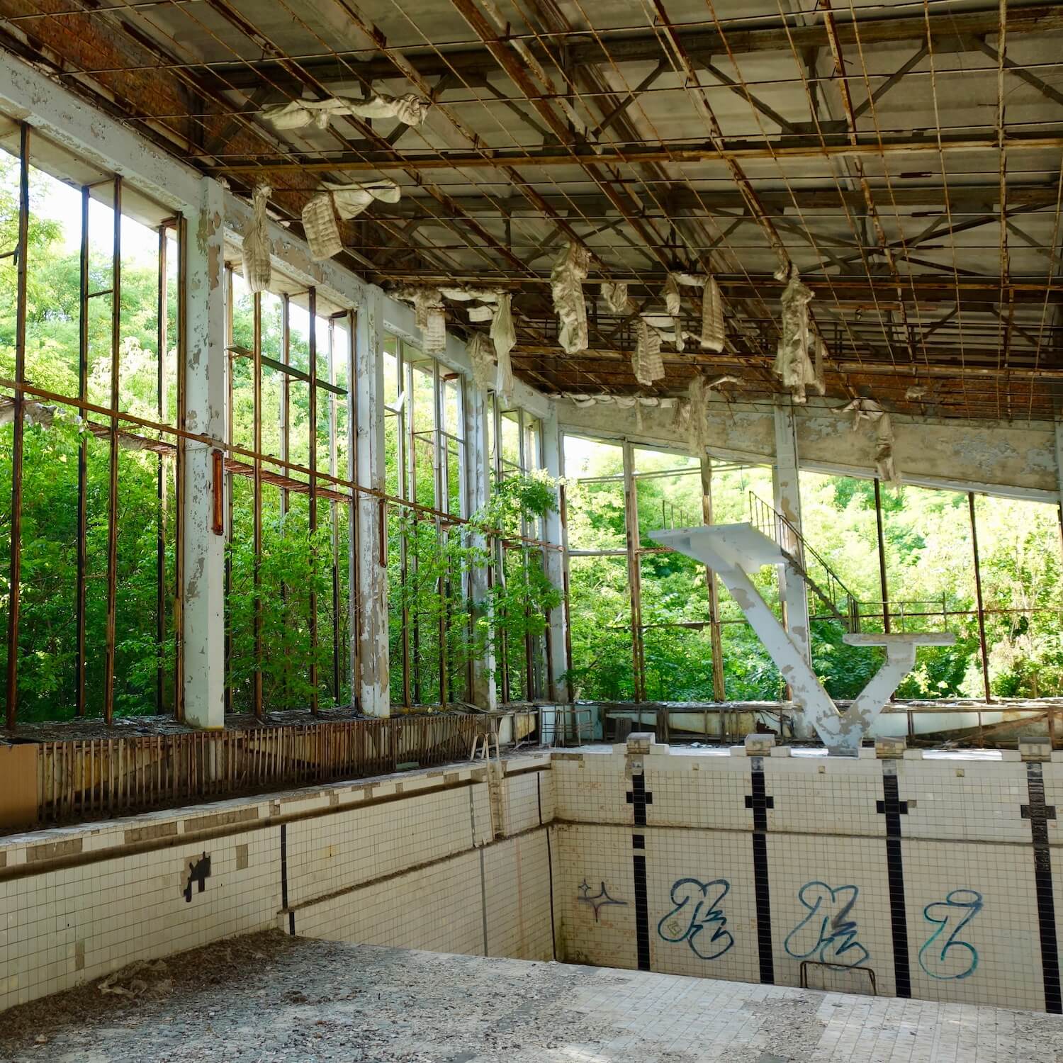 Empty swimming pool in the aquatic complex with all windows broken out and tiles hanging from the ceiling in the ghost town of Prypyat, which was abandoned following the April 1986 explosion of Chernobyl Reactor #4