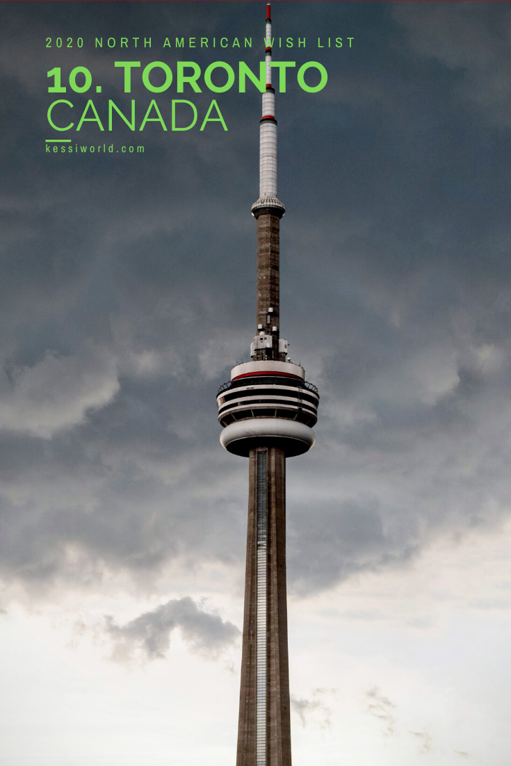 Toronto is the final photo in this set of 10 places in North America to visit in 2020.  The Canadian National Tower is the main feature of the photo with gray stormy clouds in the background.  