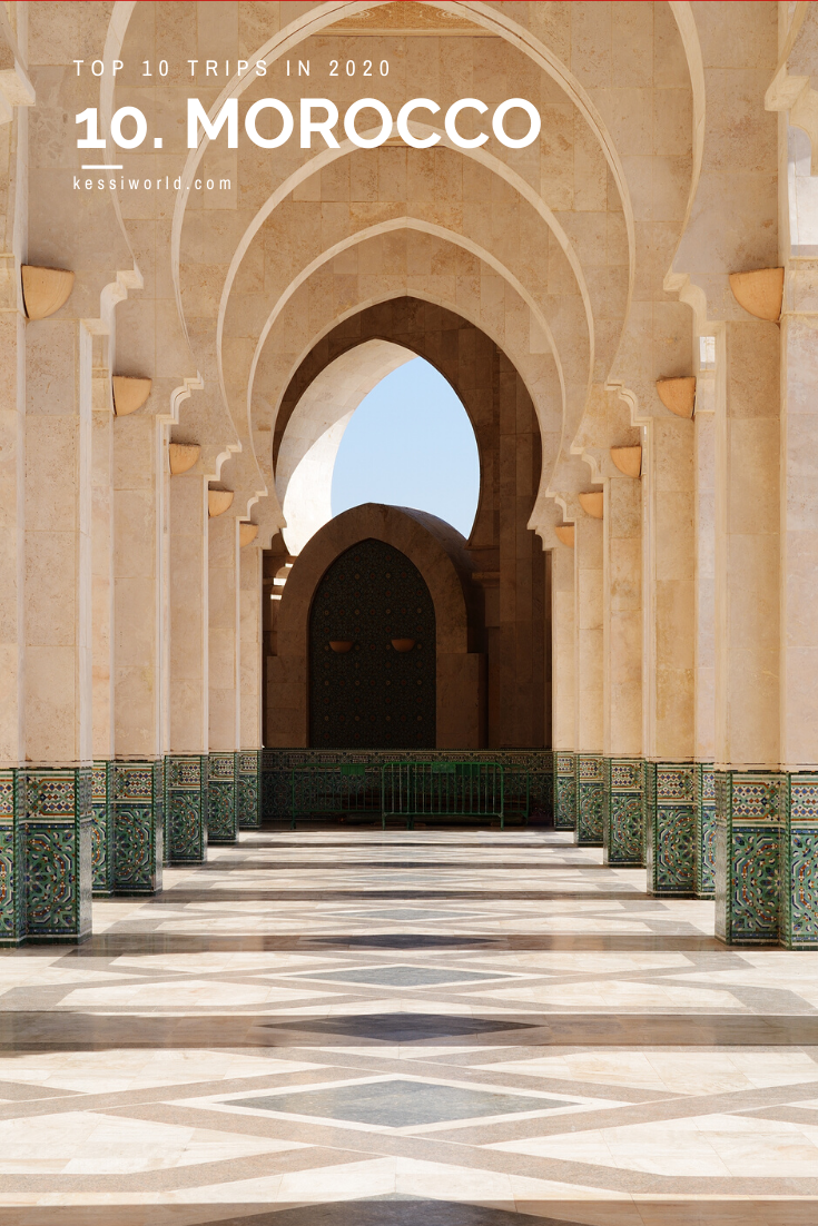 This shot is looking into a mosque in Morocco with arching white marble ceiling lines and jade green bases to the columns. The flooring is ornate with an intricate woven design.