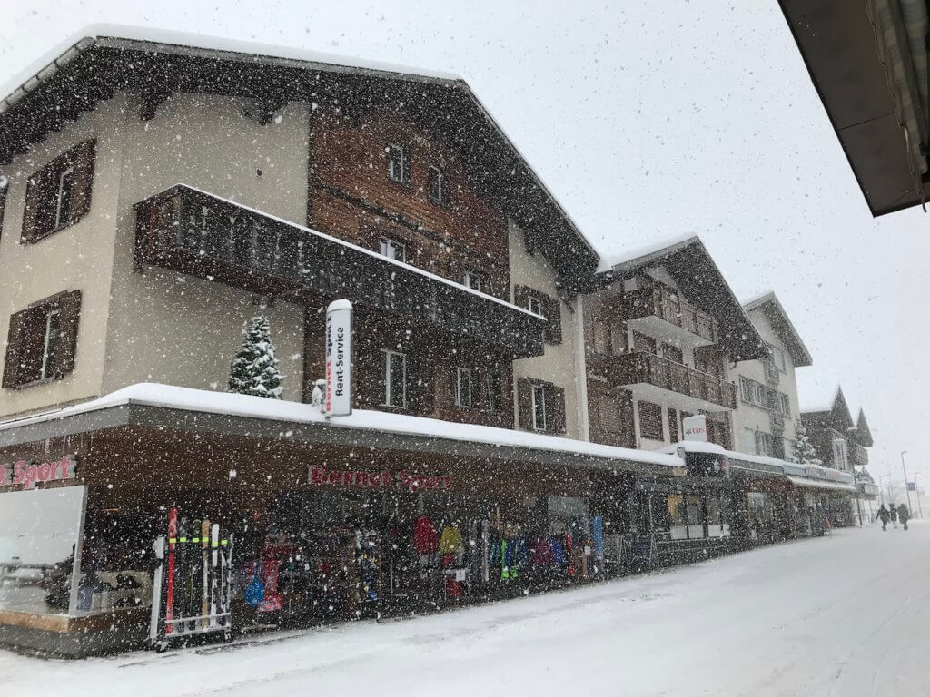 Blizzard flurry of snow covers the Main Street of downtown Grindelwald. This view shows a ski rental shoppe displaying their items with endless dots of snow falling.