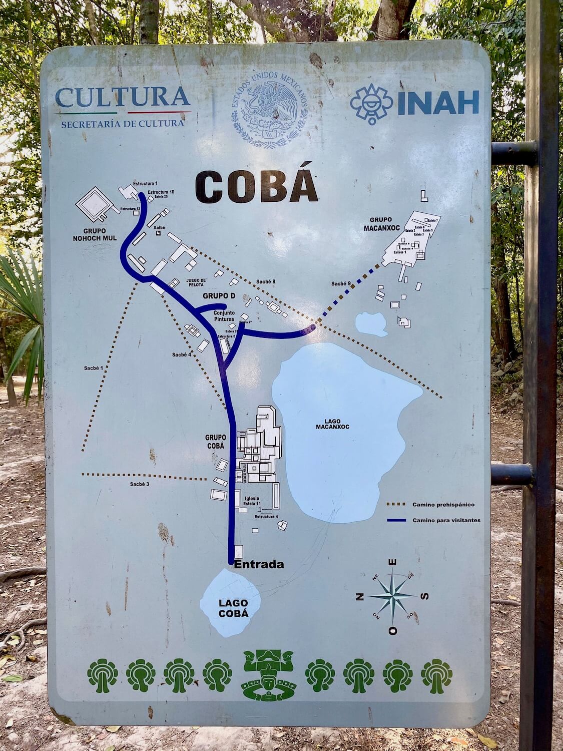 Metal sign showing a map of the ancient Mayan Ruin site of Coba, including the large lakes Lago Coba and Lago Macanxoc and the dark blue pathways available for visitors making their way through the park. 