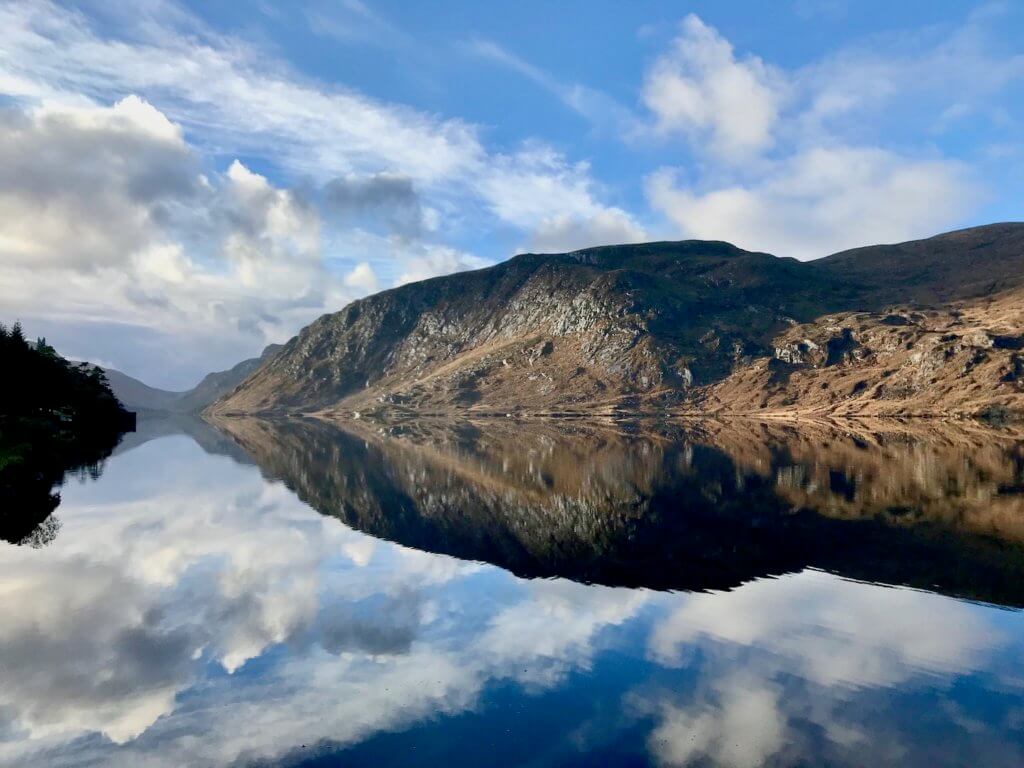 The beautiful Loch at Glenveagh National Park is a perfect mix of placid water, reflecting the massive hills of granite and tight green grass as well as the blue sky with puffy white clouds.  