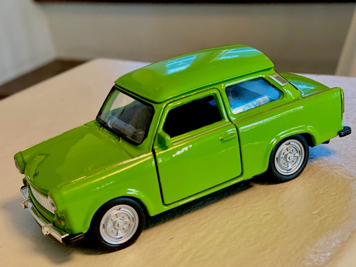 Souvenir from Berlin. Miniature size model of a former East German Trabant vehicle. The car is lime green coupe version with tiny doors and wheels with silver hub caps.
