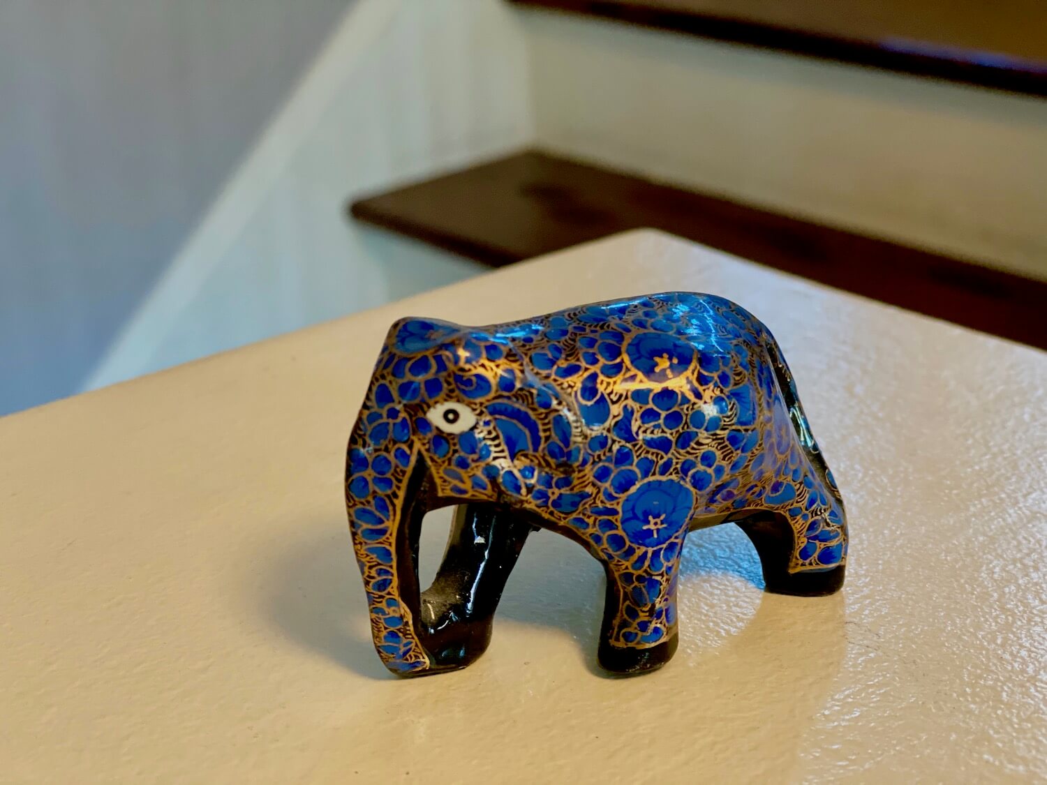 This is a brightly painted miniature elephant from Kashmir region of India painted with bright gold lines outlining cobalt blue shapes. The figures underbelly is black and there is a white eye looking at the camera.  The elephant is one of my favorites because it's a souvenir with soul. 