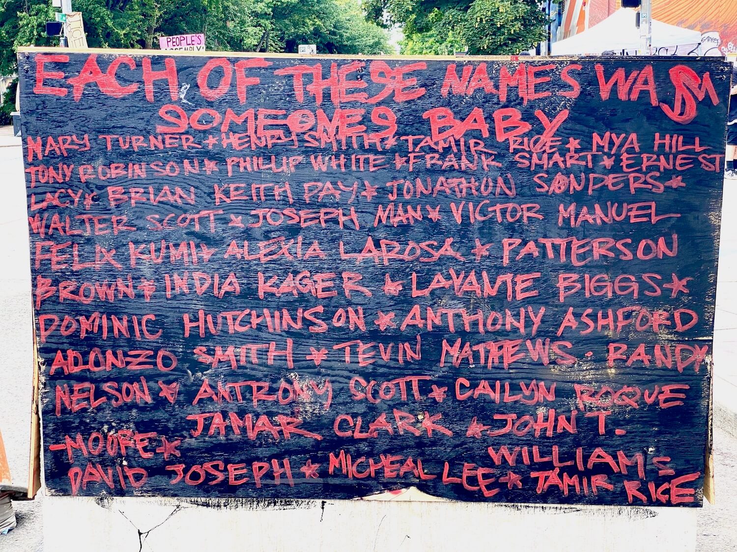 A sign on one of the painted traffic barricades in the Black Lives Matter protest zone in Seattle on Capitol Hill.   This barricade is painted black with red letters that read, Each of these names was someones baby and over 20 names are listed below. 