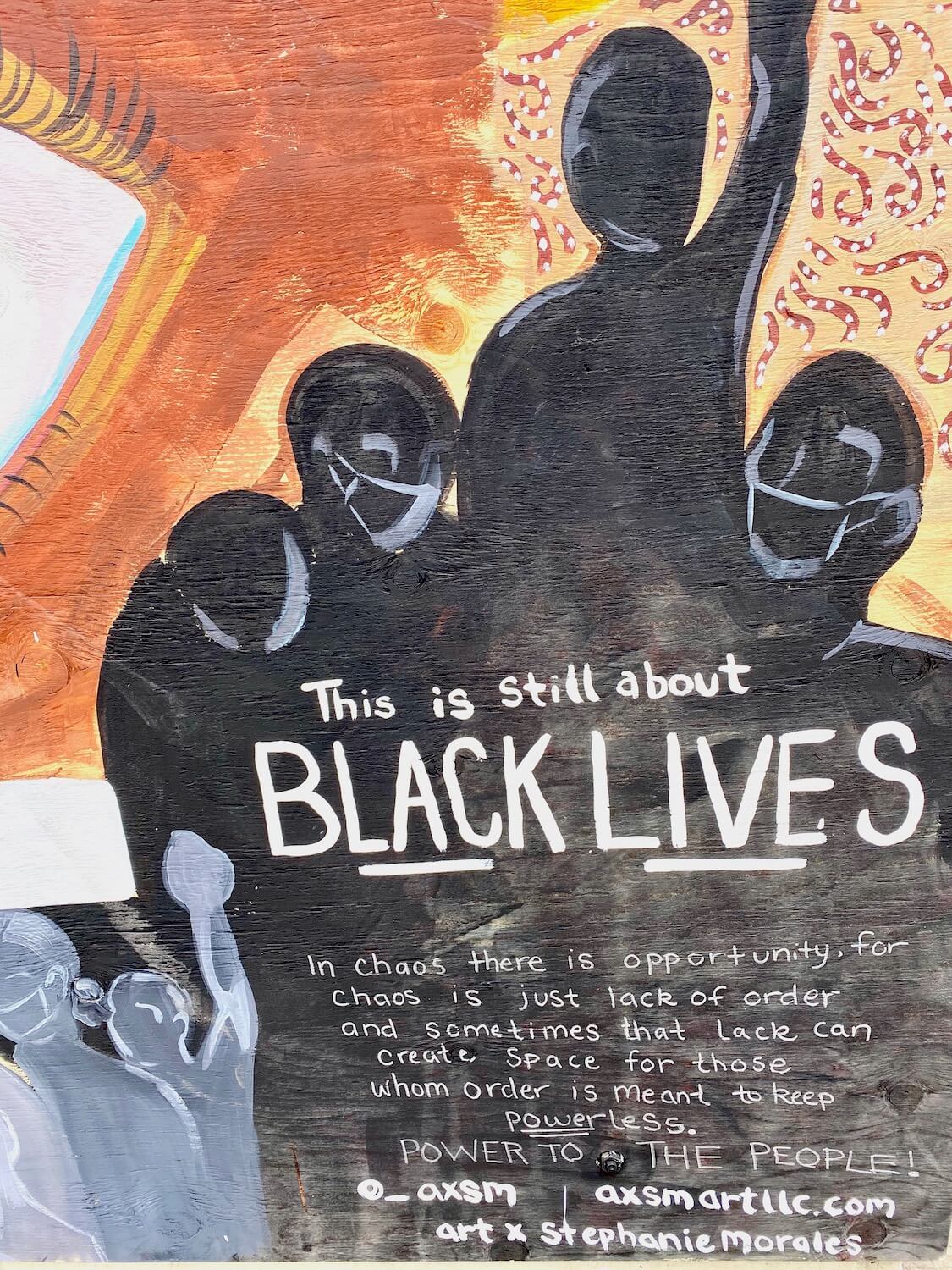 A barricade in the CHOP zone of Seattle's Capitol Hill in Seattle has painted plywood with an art mural containing black figures raising fists up to the sky with messages about Black Lives Matter. 