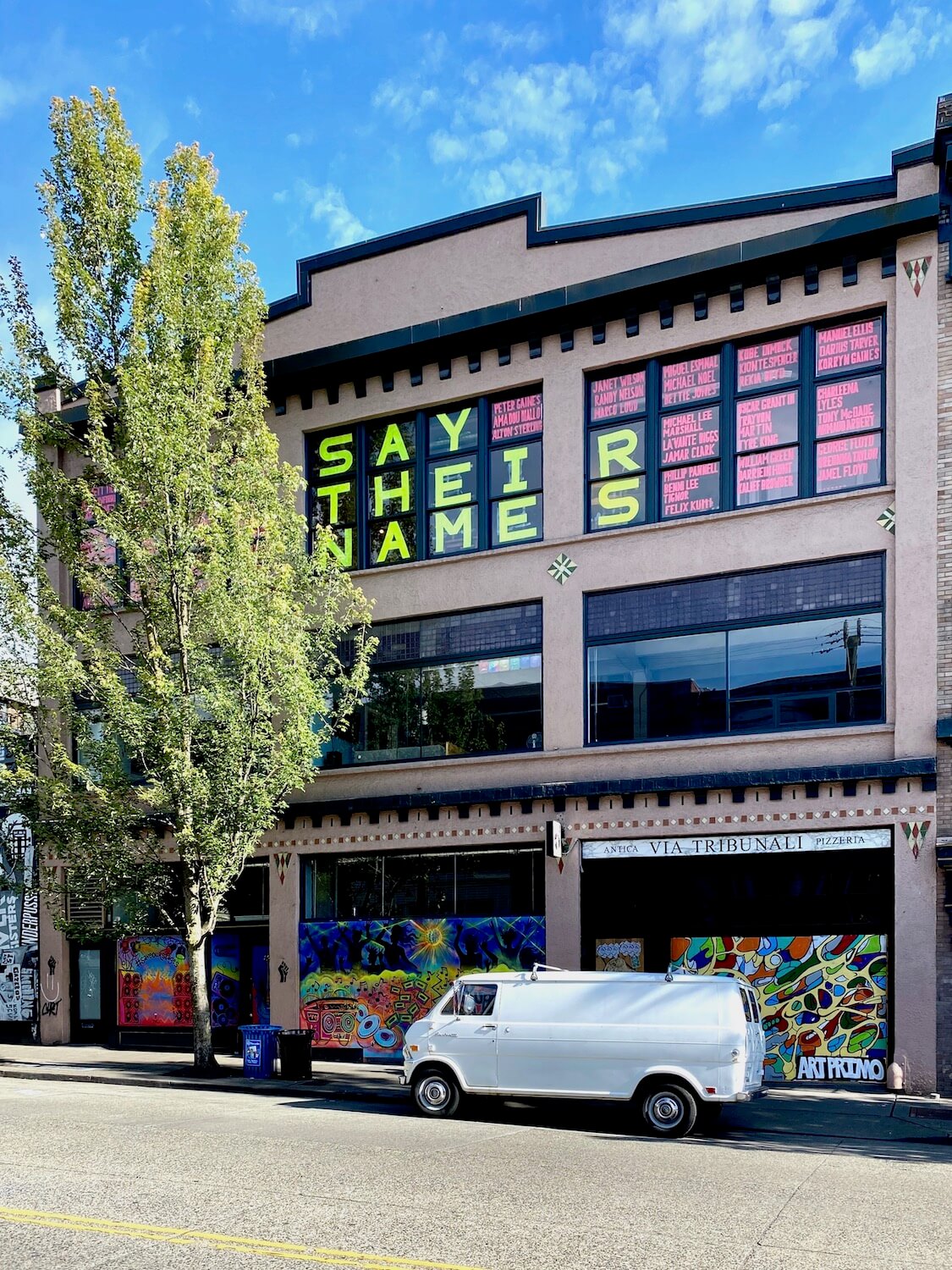 A three story commercial budding in the Capitol Hill neighborhood of Seattle has bright yellow letters on the windows of the top floor that spell out, Say their names.  