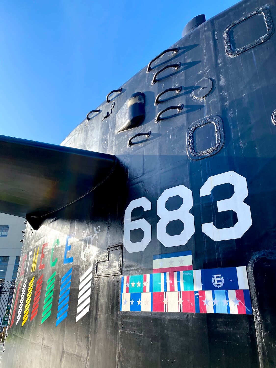 An up close photo of the sail of the USS Parche is great thing to visit in Bremerton on a day trip from Seattle.  The sail is painted black with white numbers and the sky is blue above. 