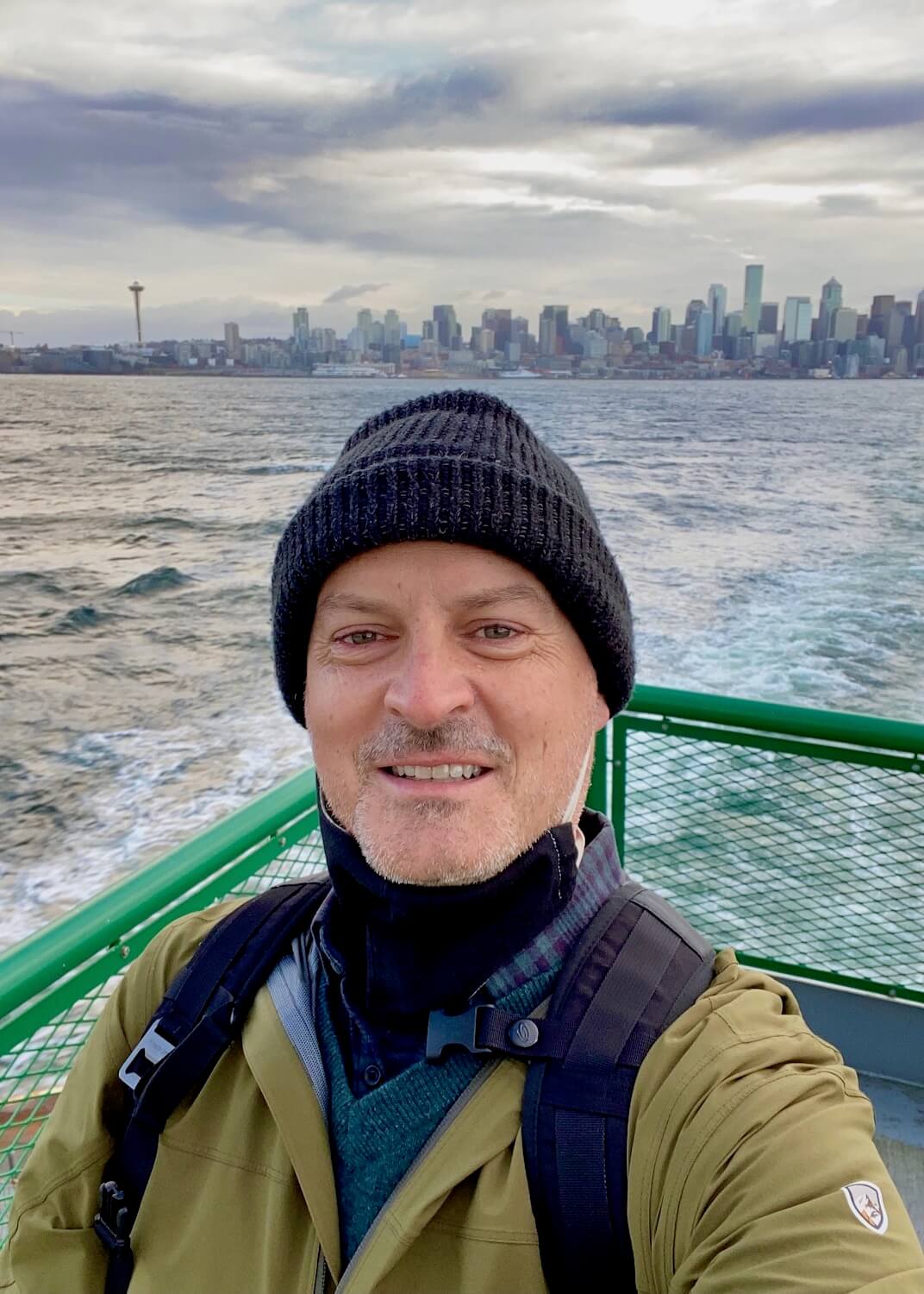Selfie of Matthew Kessi on a Washington State Ferry with the skyline of downtown Seattle, including the Space Needle in the background beyond the gray waters of the Salish Sea