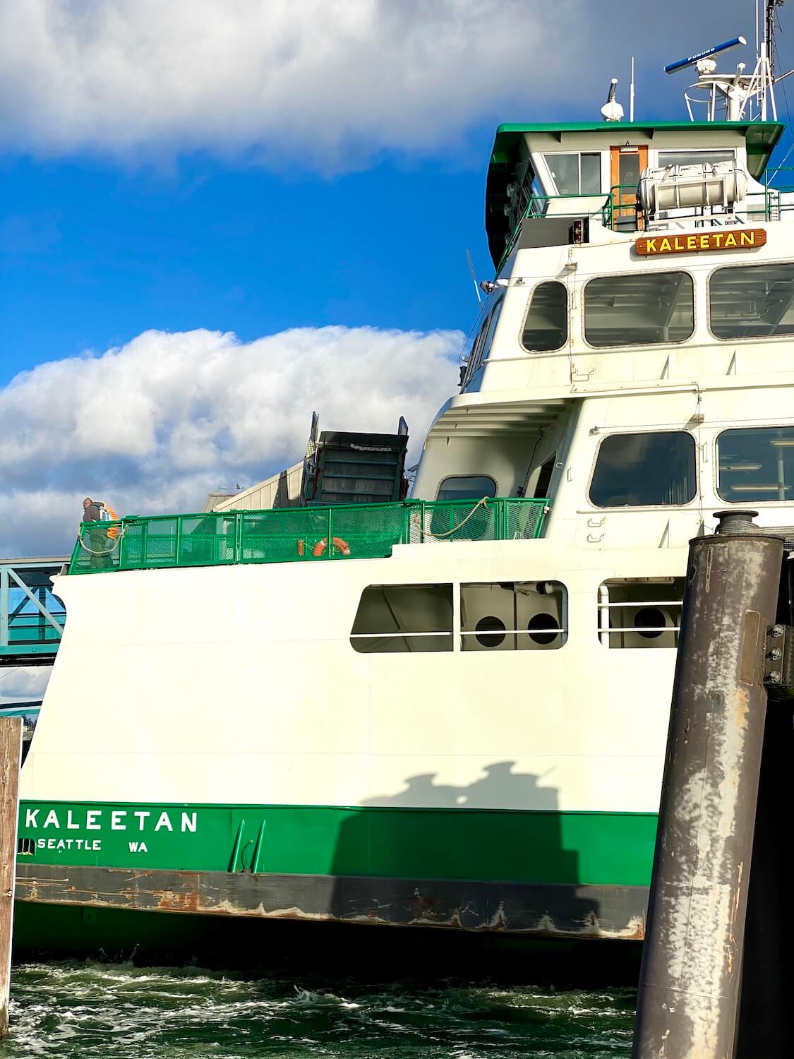 A close of photo of the ferry Kaleetan, sailing into the dock in Bremerton, Washington.  The ferry is white with green accents, including a bright green deck railing.  