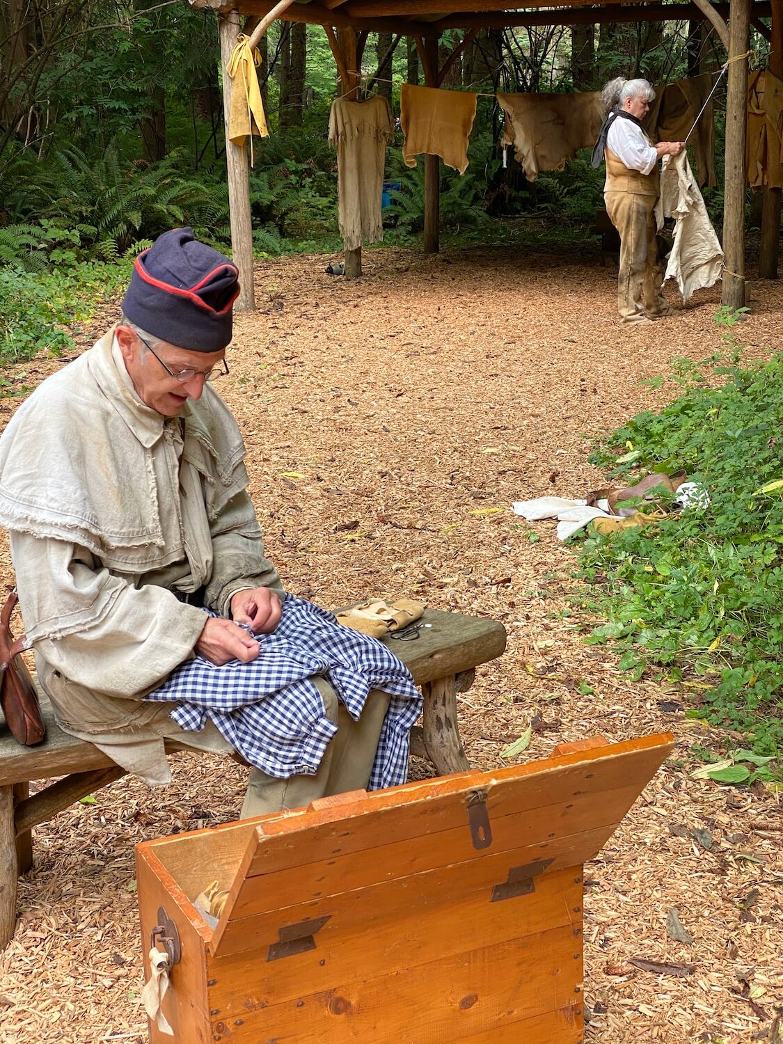 A man wearing clothing common around 1805 when the Lewis and Clark expedition arrived at Fort Clatsop, sews clothing in preparation for Winter.  This interpretive scene is part of the exhibit at the Lewis and Clark National Historic Area.