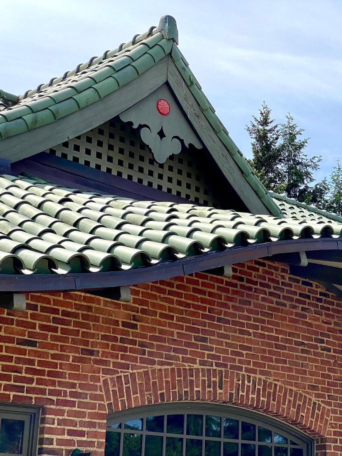The pagoda at the Japanese Garden at Point Defiance Park in Tacoma, Washington has an ornate roofline with green curved tile while the face of the building holds historic looking red brick.  