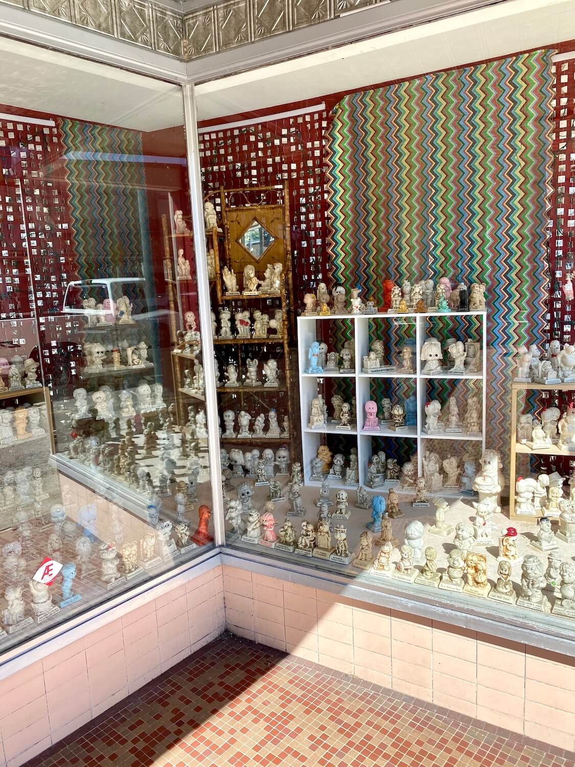 Window shopping is a fun thing to do in Astoria, Oregon and this shop displays hundreds of small kitschy figurines in the window as a beam of sunshine graces the mosaic of the ground.