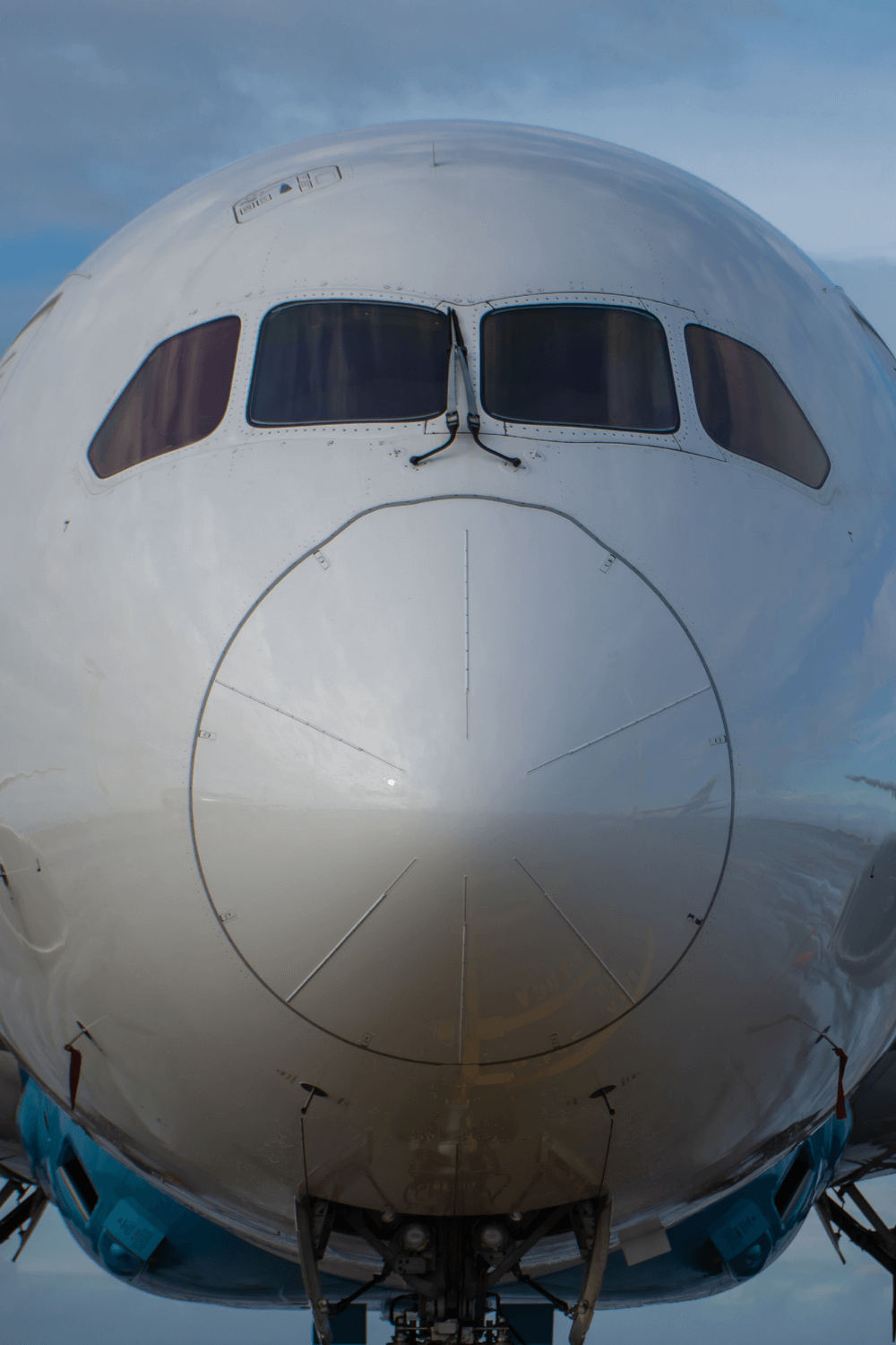 An airplane at Boeings Factory in Everett Washington close up upon the nose. The cone of the plane adds texture while four windows from the flight deck seem to pear out.