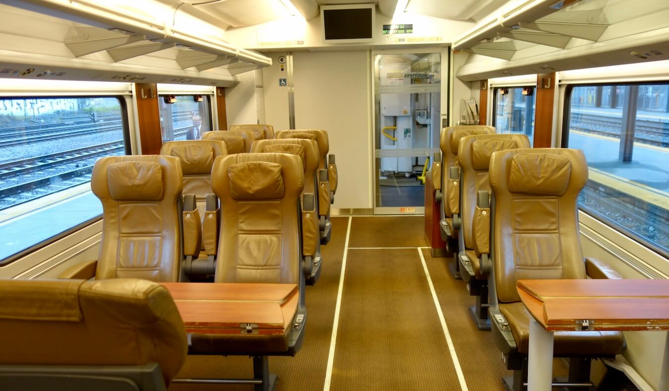 The business class section of the Amtrak Cascades train from Seattle to Vancouver offers three abreast seating with plush leather seats and card tables made of a cherry wood.