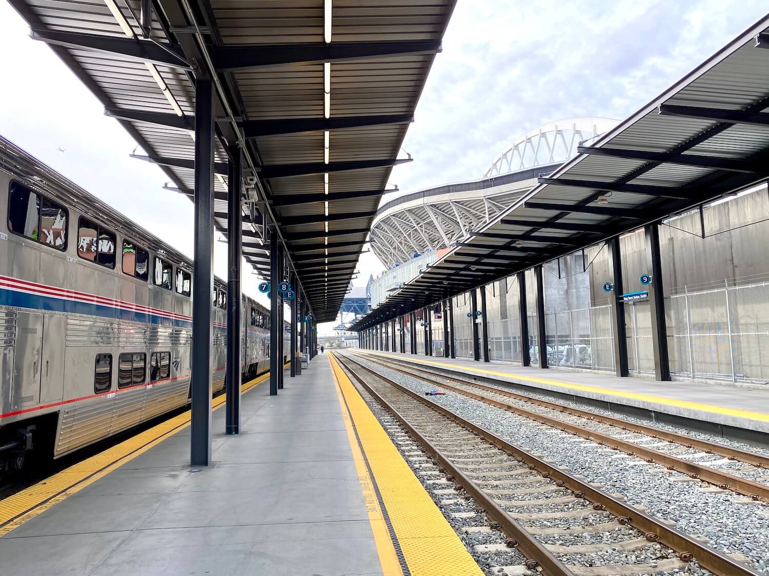 The Seattle King Street Station is the terminus for the train to Vancouver. Here, yellow warning lines remind travelers to stay away from the tracks, which are shown leading away from the station.
