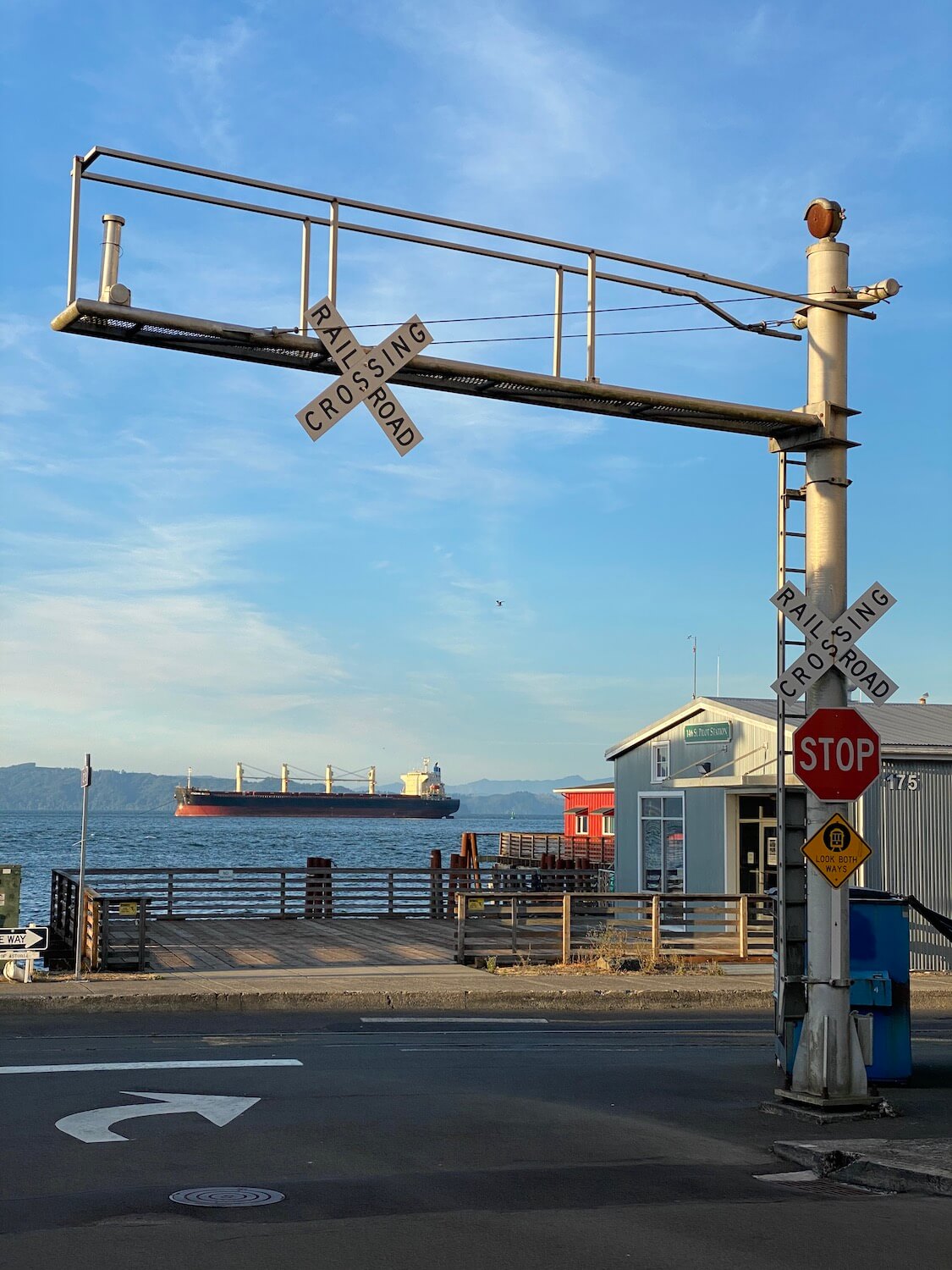 A railroad crossing sign frames in a large tanker in the waters of the Columbia River.  The Astoria waterfront is a great place to explore while on a weekend getaway. 