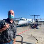 Matthew Kessi deplanes from his Alaska Airlines flight after using frequent flyer miles to fly to Redmond/Bend Airport for a quick getaway. He's wearing a face mask and carrying a backpack.