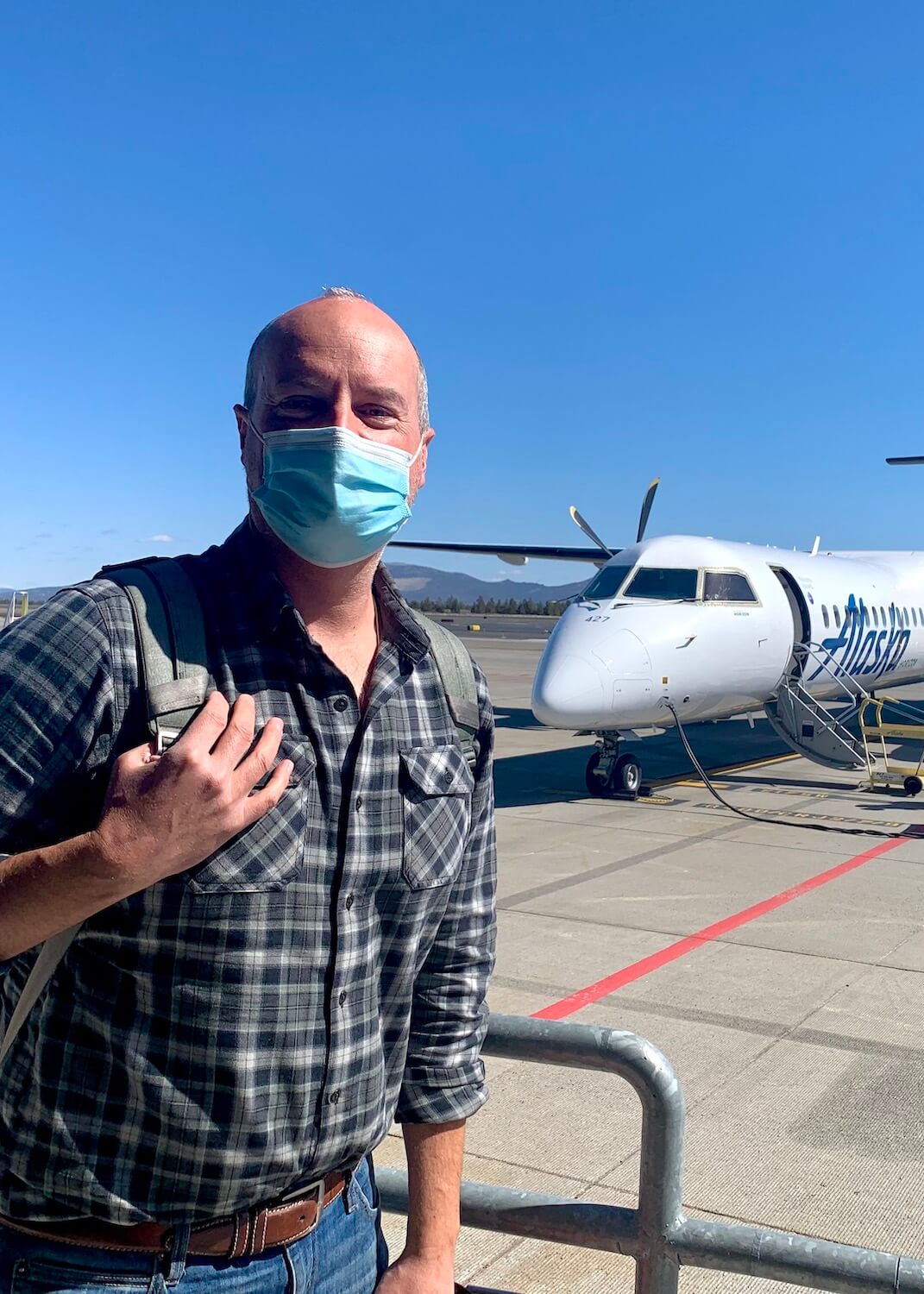 Matthew Kessi deplanes from his Alaska Airlines flight after using frequent flyer miles to fly to Redmond/Bend Airport for a  quick getaway.  He's wearing a face mask and carrying a backpack. 