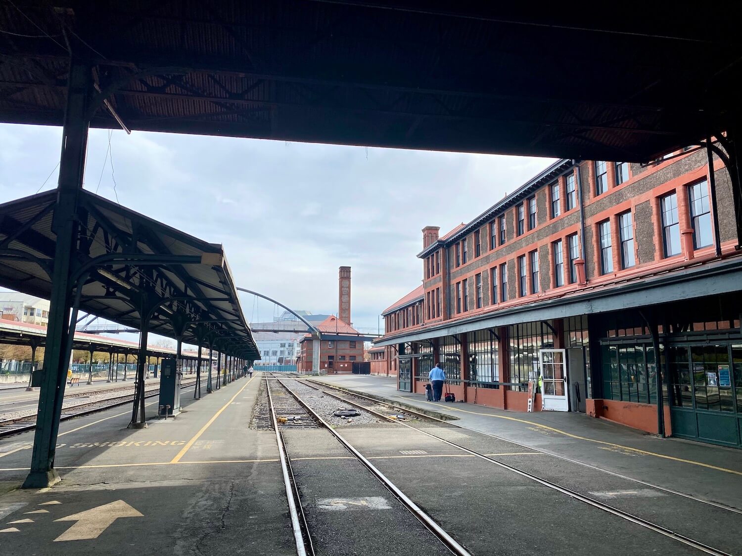 This photo shows a train from Seattle arriving in Portland at Union Station. The famous red brick building can be seen from under a dark overhang shelter where the train tracks roll through the station.