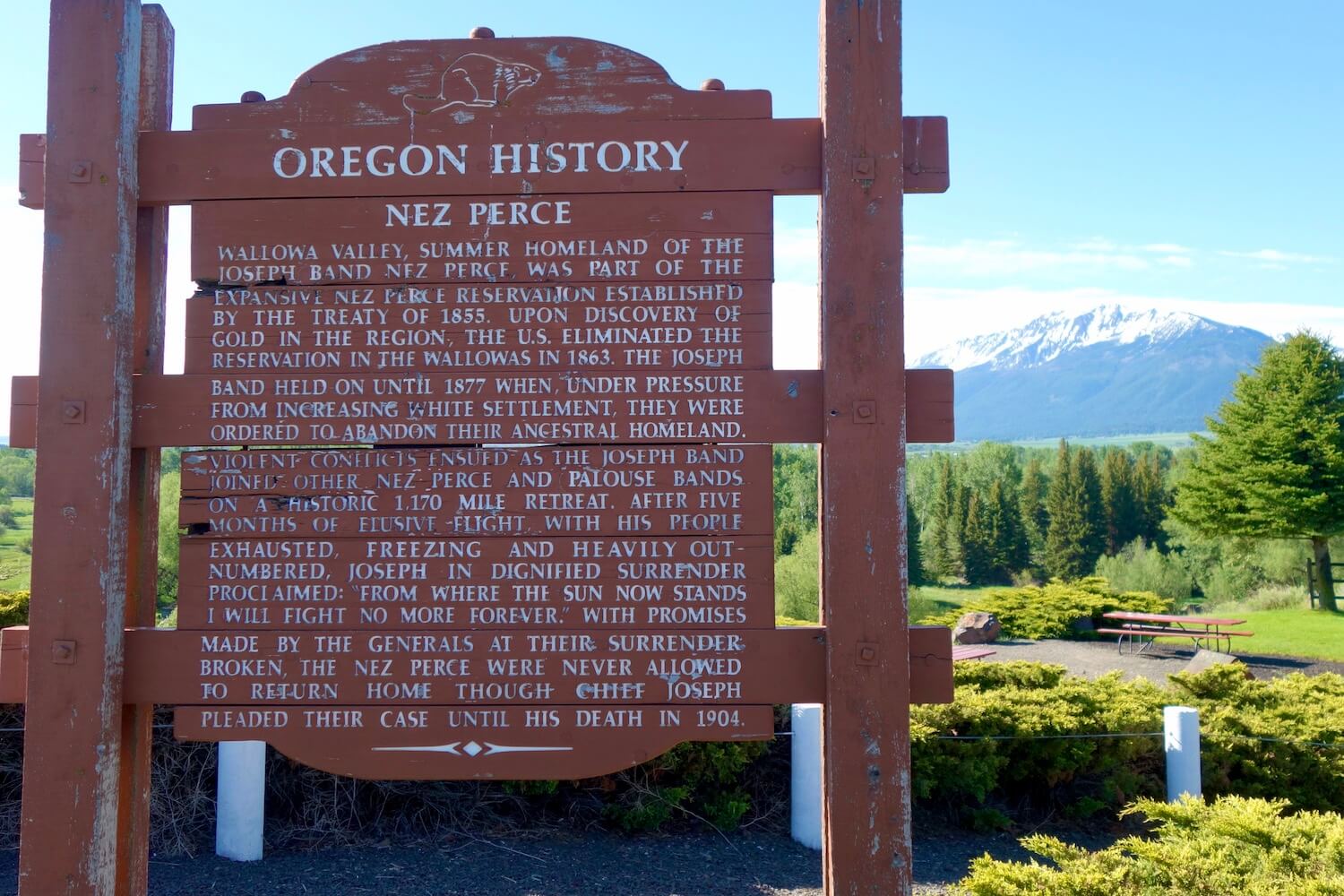 An Oregon History side on the side of the road is worn red painted wood with white letters that briefly describes the Nez Perce people who used to live in this region that is present day Joseph Oregon.  