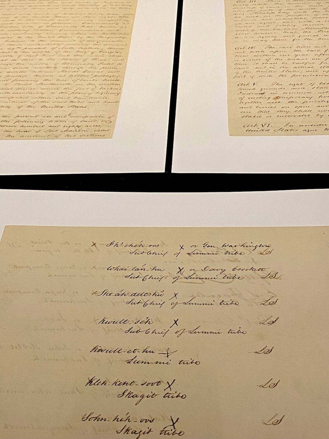 A photo from the Hibulb Cultural Center of the Point Elliott Treaty, which is on display.  Here the parchment paper can be seen with black calligraphy letters followed by X's for each Indian signatory of the 1855 event. 