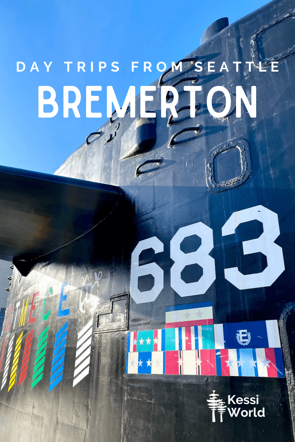 This Pinterest pin displays white letters that read "day trips from Seattle" and highlights Bremerton. The photo is the top of a decommissioned submarine with bright white letters that show the number of the vessel and colorful award ribbons painted onto the shining black finish.