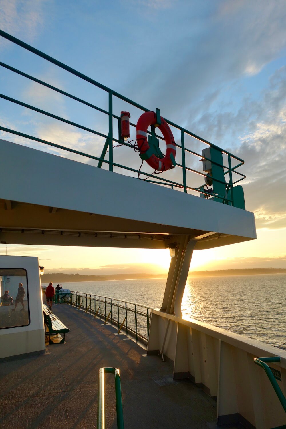 Sunset on a ferry traveling between Seattle and Bainbridge Island. The upper deck of the ship reflects the sunshine off the metal structure as well as the Salish Sea