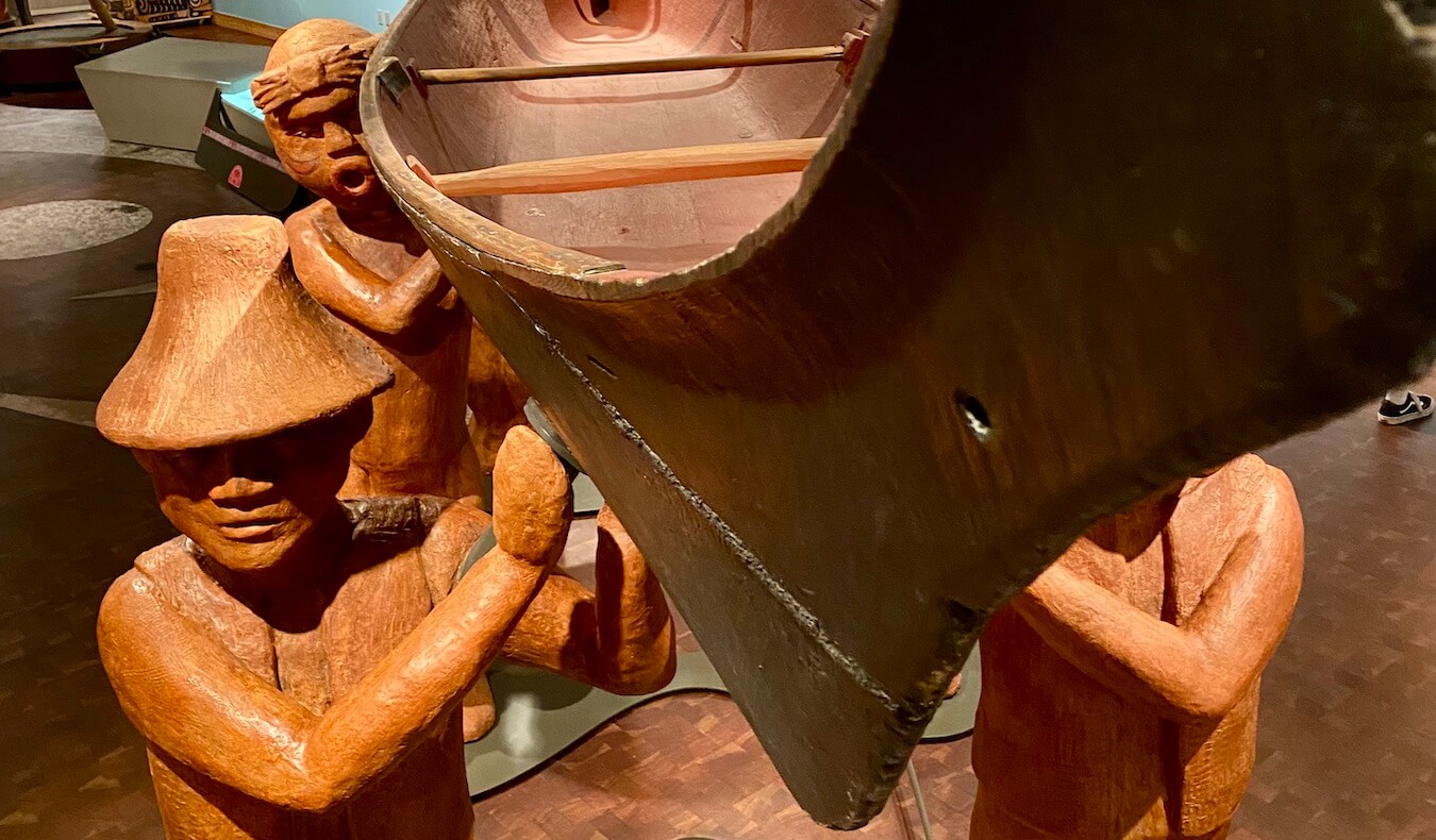 Wooden figures carved from cedar hold up a canoe, also carved from cedar at the Suqaumish Museum on the Kitsap Peninsula.  