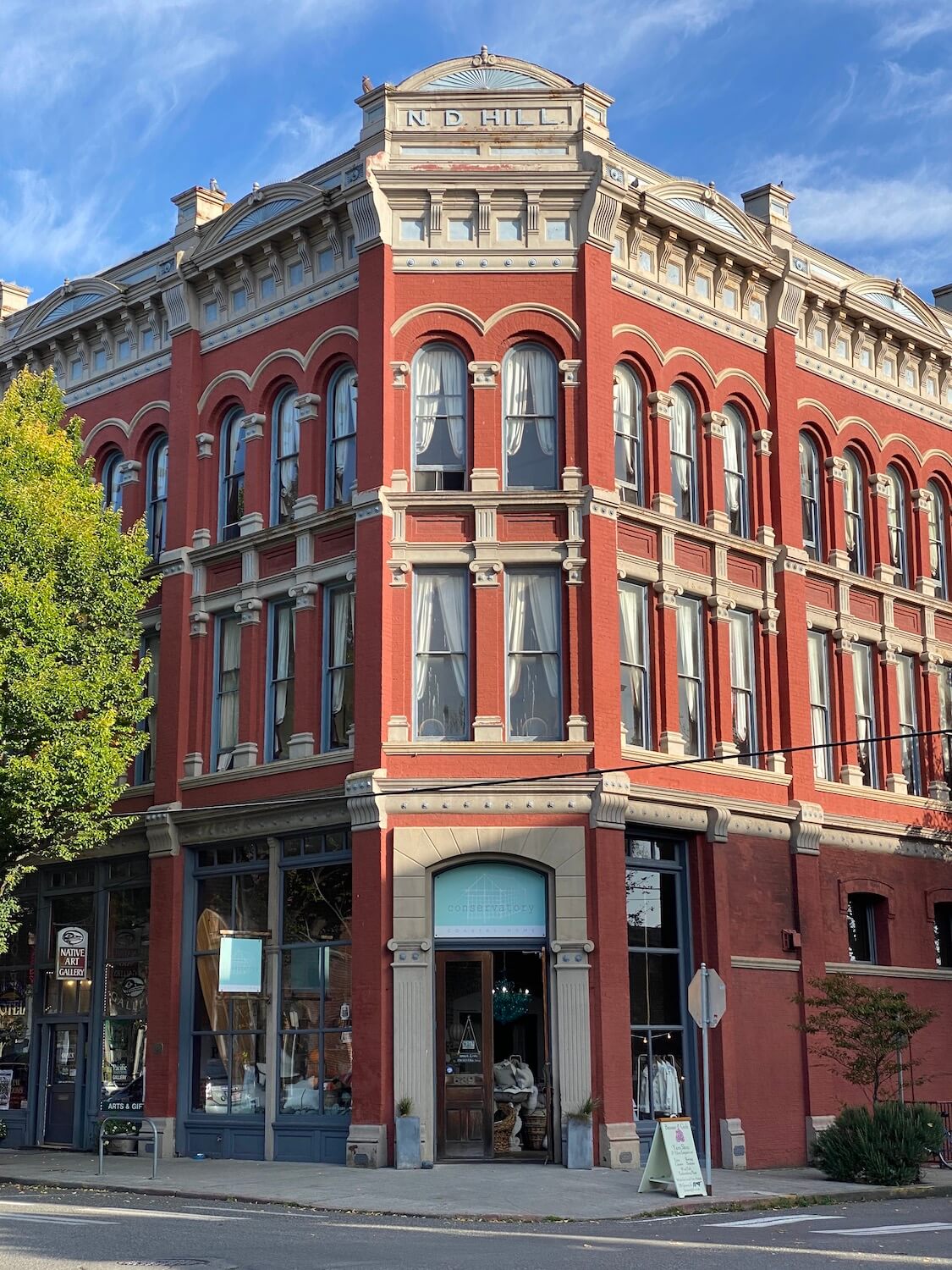 An ornate Victorian building is painted red brick and gray accents and sits under a blue sky. This is on Water Street in Downtown Port Townsend, Washington. A fun thing to do here is look at all the historic buildings.