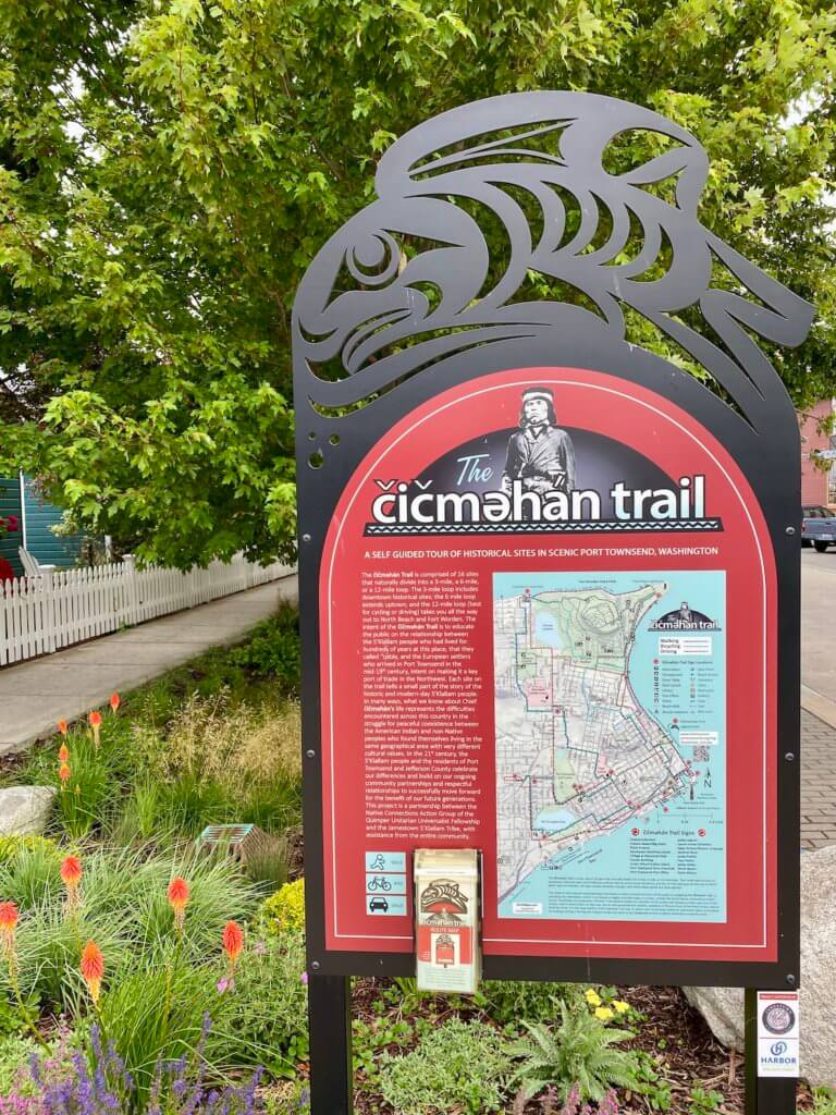 The cicmehan trail is an 18-stop 12-mile hike around the city of Port Townsend and is educational with information about Native American history in the area. The sign is black metal with native fish art on top while the placard is red with white lettering.