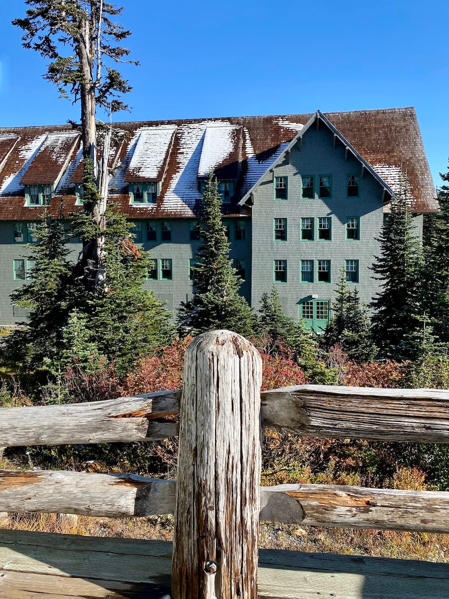 Paradise Inn has a light dusting of snow on the wooden shake roof while an old wooden fence holds the foreground of the shot.
