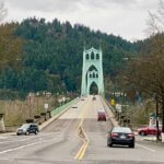 The St. Johns Bridge rises up toward Forest Park in Portland. There are a few cars coming and going.