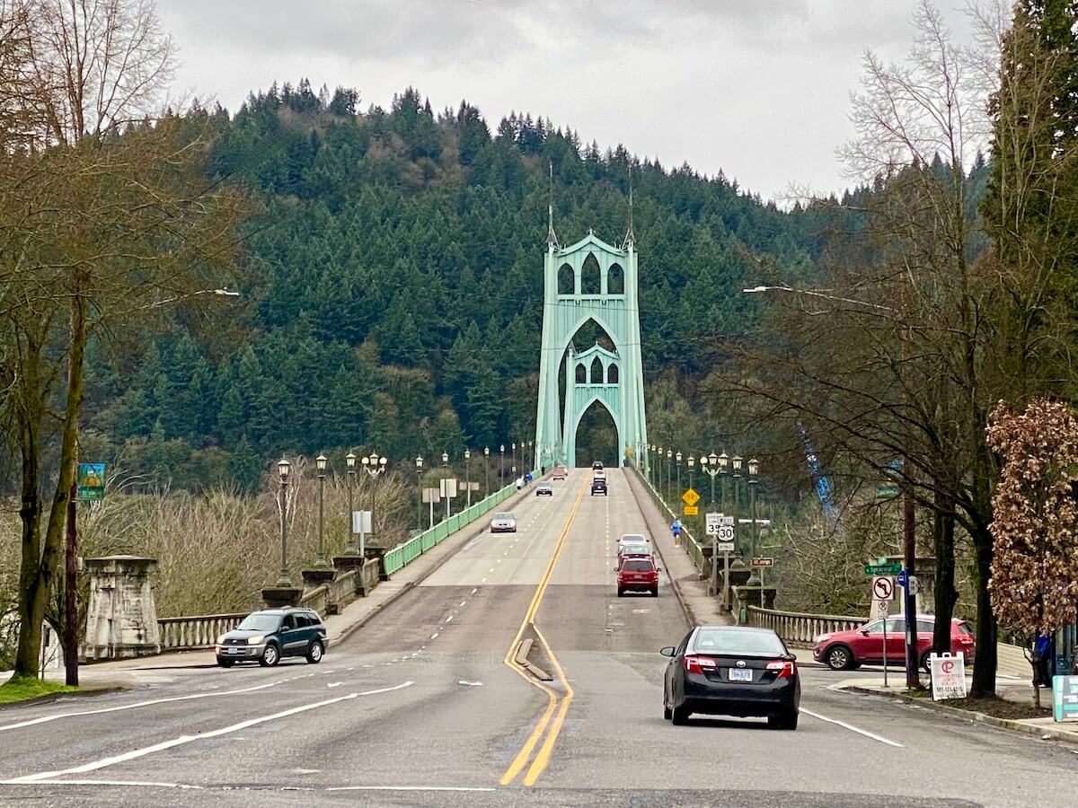 The St. Johns Bridge rises up toward Forest Park in Portland. There are a few cars coming and going.