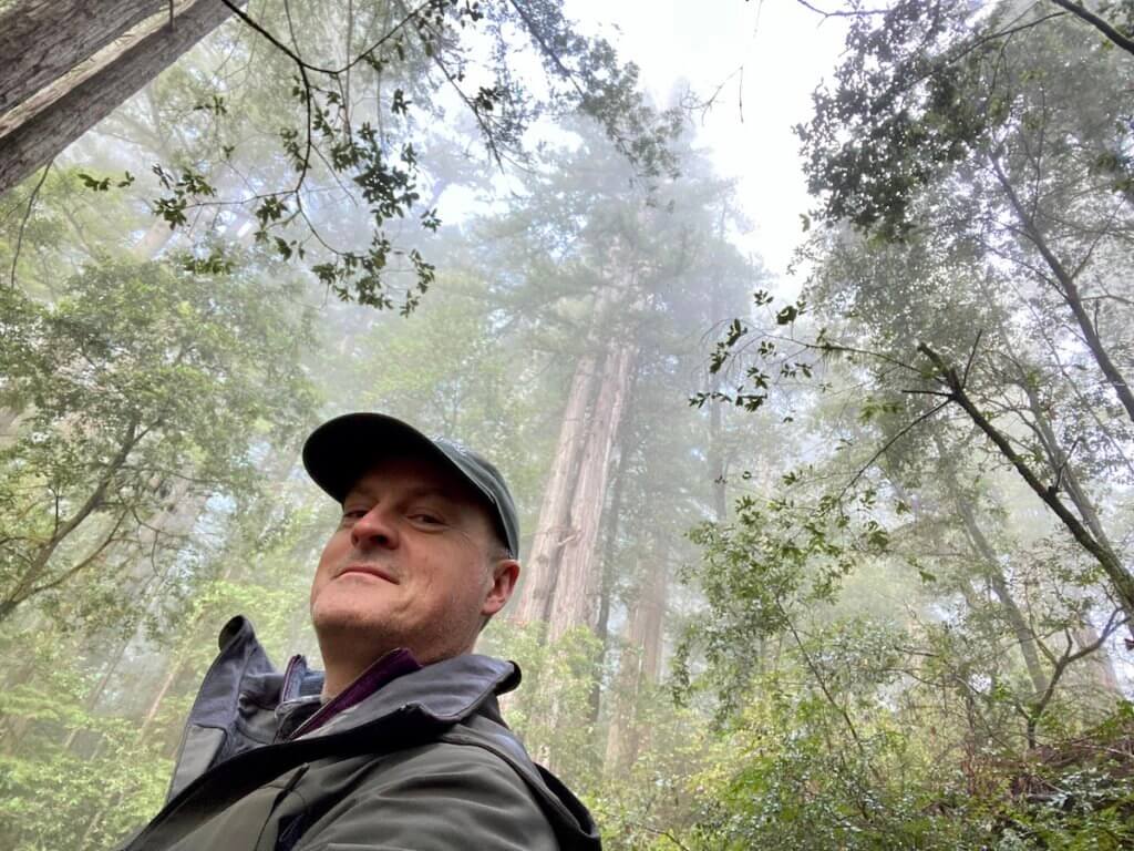 Matthew Kessi smiles for a selfie among a redwood forest near Brookings Oregon