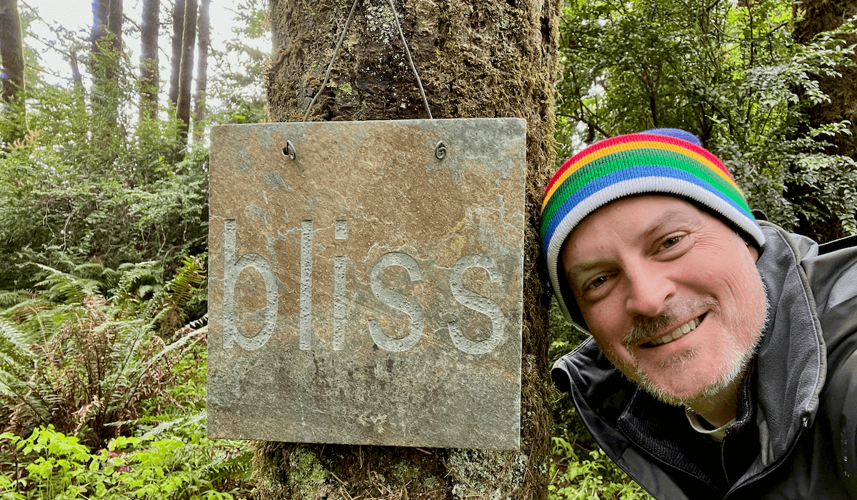 Matthew Kessi poses, smiling next to a sign that reads "bliss" etched into a slate tile. He's happy because he gets to stay at a unique hotel on the Oregon Coast.
