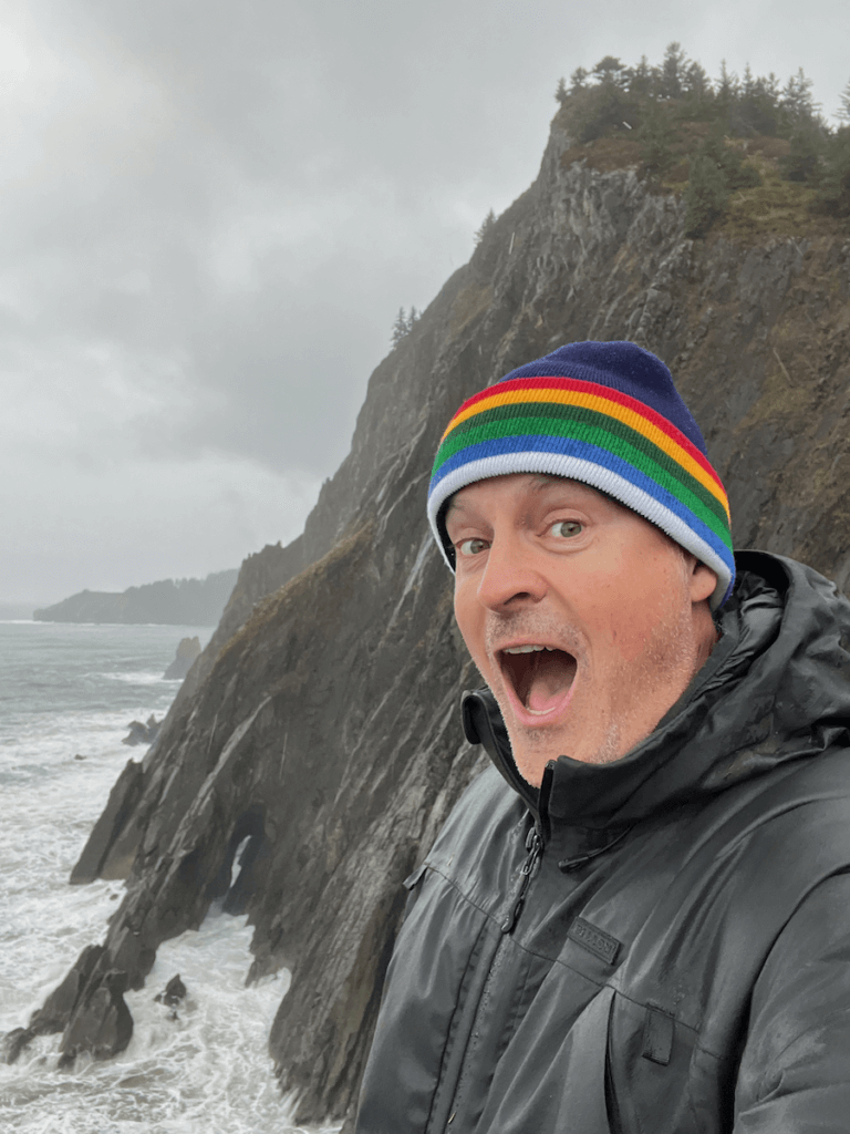 Matthew Kessi poses for a selfie at a dramatic viewpoint overlooking the angry waves of the Pacific Ocean crashing against rock stacks at Oswald West State Park.