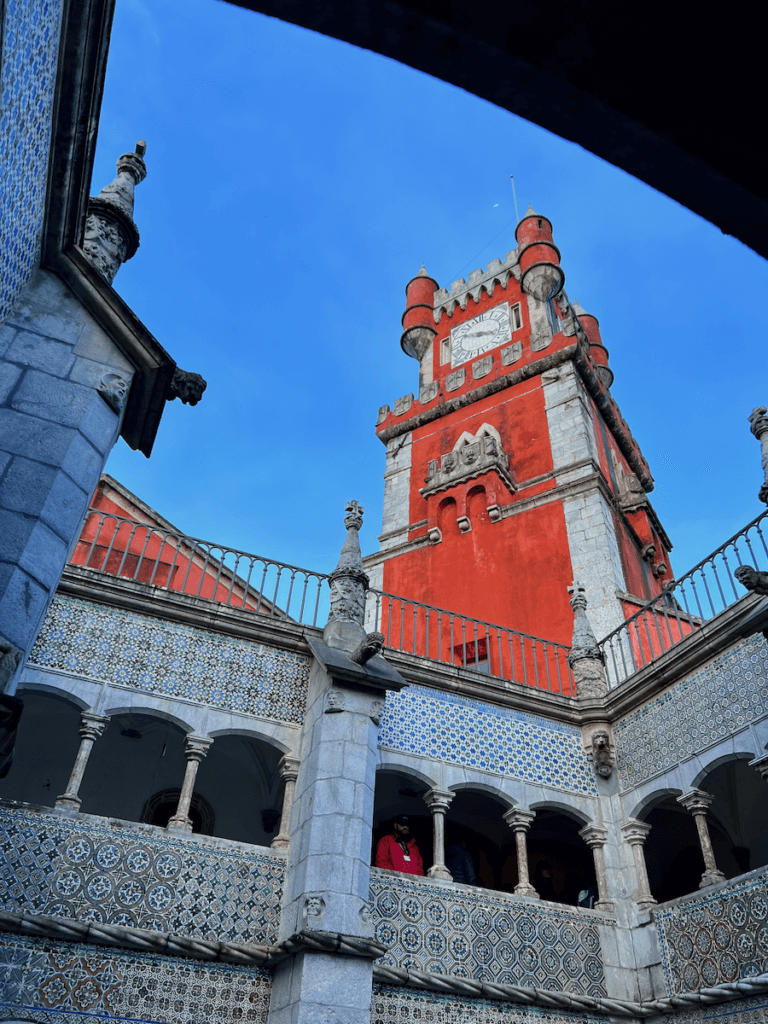 A brilliant orange castle top at the Pena Palace in Sintra shines bright against a blue sky.