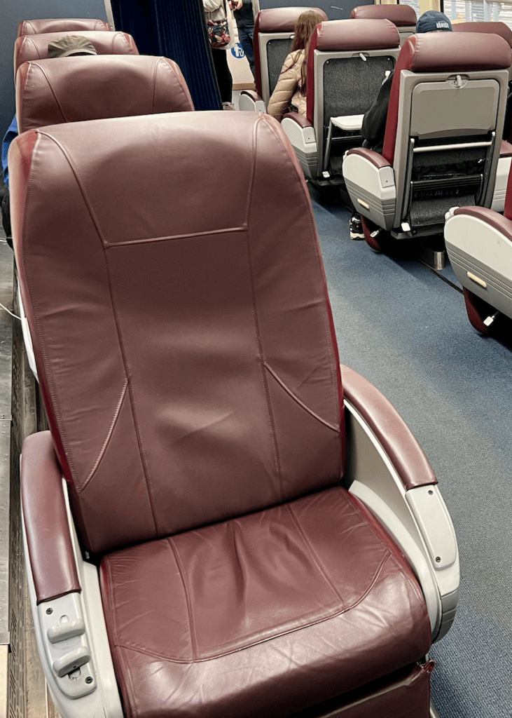 A plush burgundy leather seat in the Business Class section of the Amtrak train from Seattle to Vancouver. There are several other seats in the background.