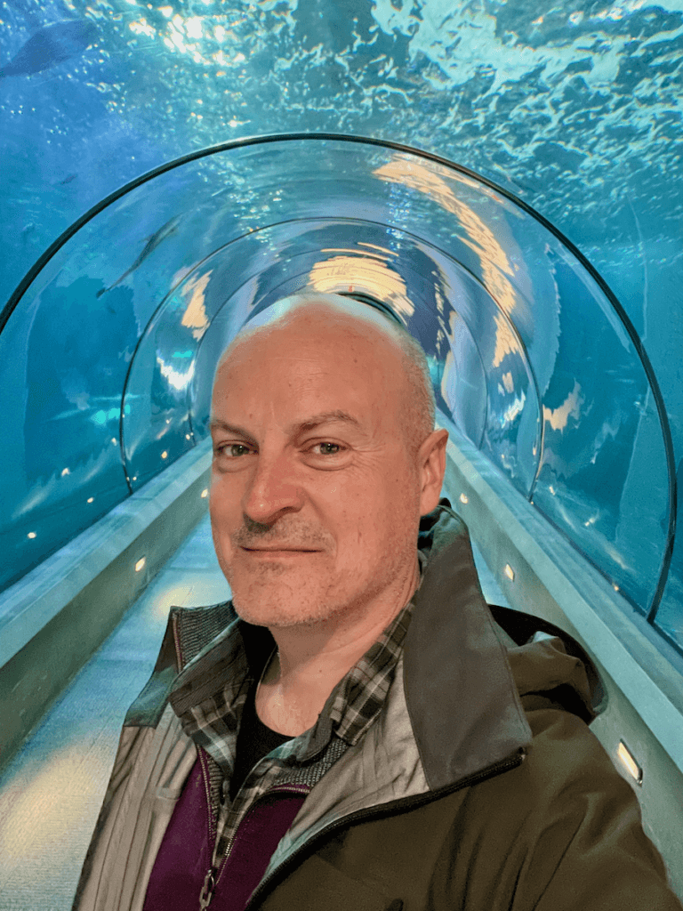 Matthew Kessi poses for a selfie under the water at the Oregon Coast Aquarium in Newport Oregon. This is a great thing to do and he's smiling against the bubbling blue water surrounding him.