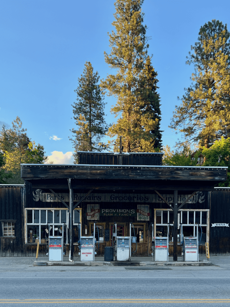 The main street of Winthrop, Washington has a gas station with old pioneer motif in the architecture under a blue sky day.