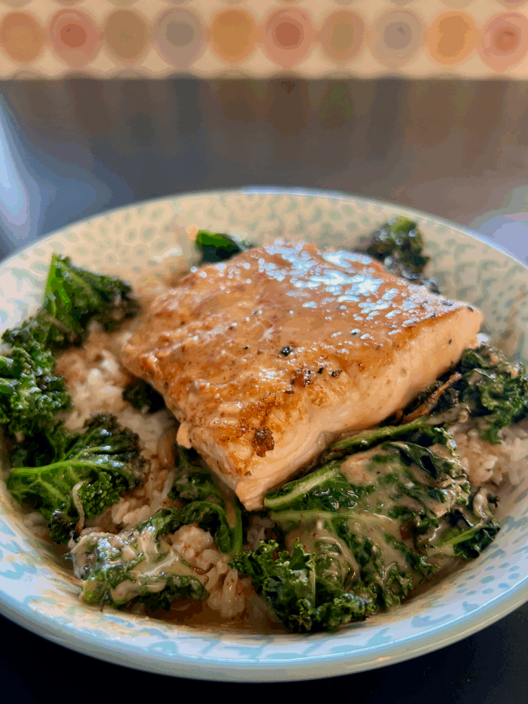 A yummy dish of salmon with a glaze sits atop greens in a porcelain bowl at a restaurant on the Oregon Coast.
