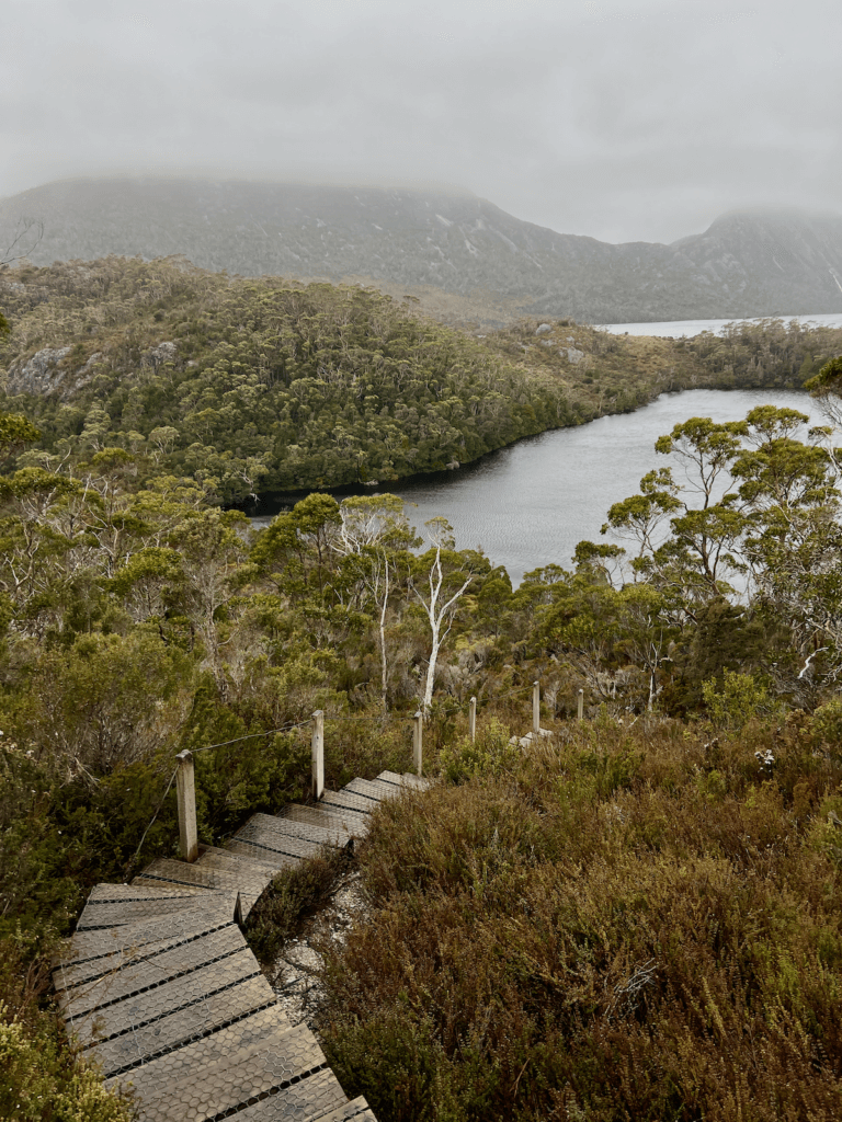 A long series of steps leads down a mountain hike toward an alpine lake as the mist floats above the lakes, covering up the mountains.